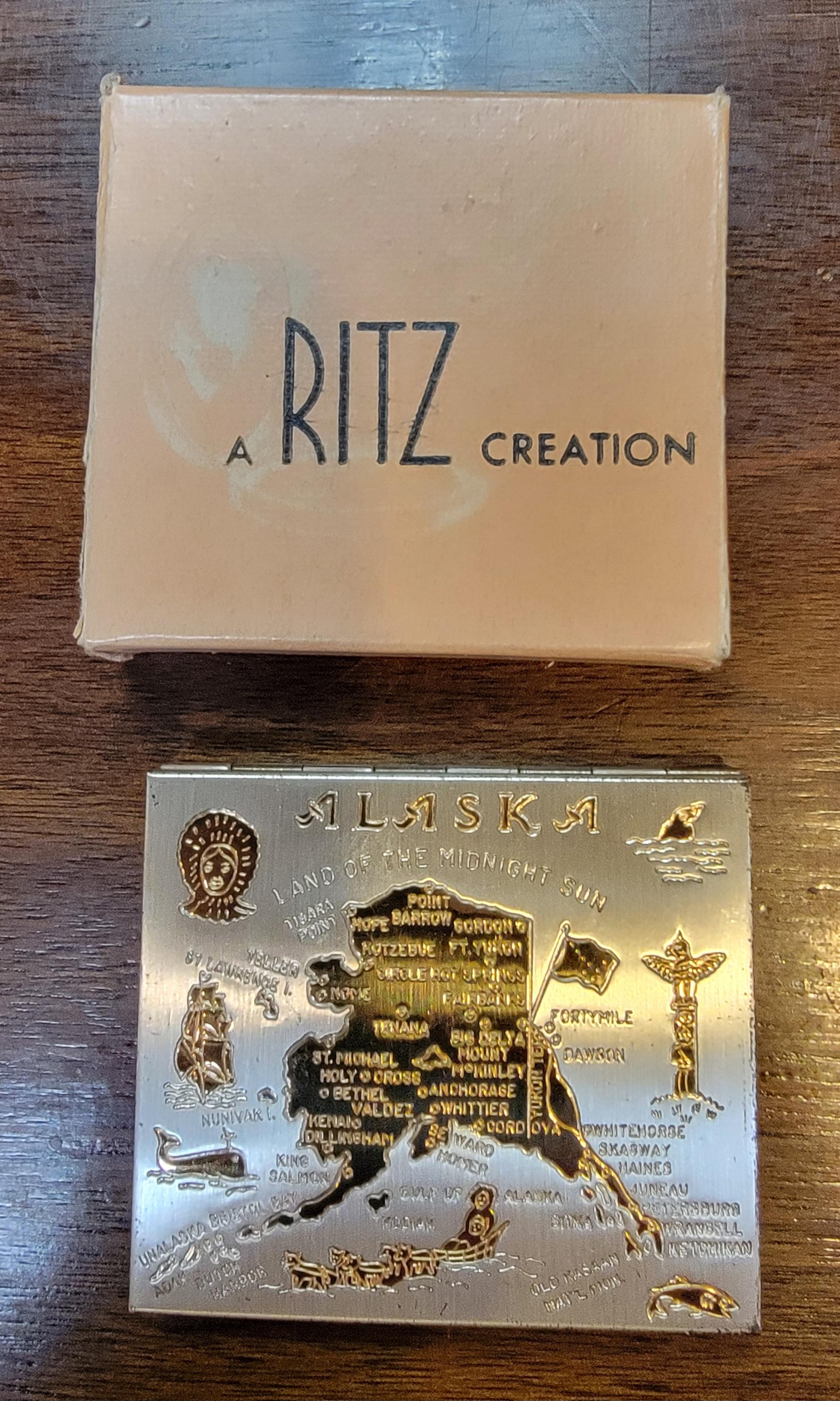 Un poudrier RITZ des années 1950 avec sa boîte d'origine représentant une carte de l'Alaska avec des points d'intérêt. Semble être dans son état d'origine, sans avoir été utilisé. 

Compact sans boîte de mesures :
2.75 pouces de large.
2,63 pouces
