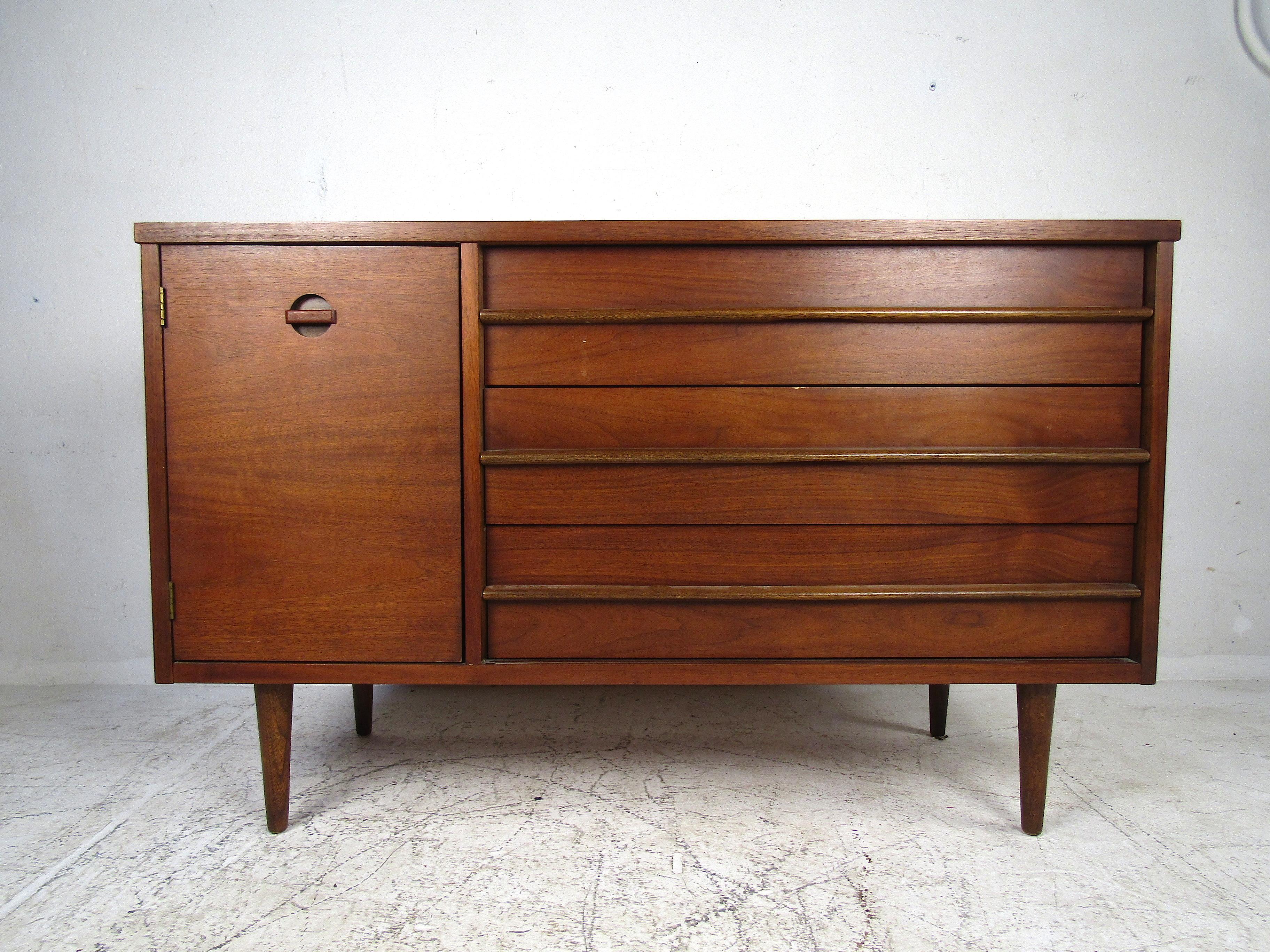 Great midcentury credenza manufactured by Basset Furniture Industries Inc. This credenza or server is a compact model that offers ample storage space without taking up much space. Three dovetail-jointed drawers and a cabinet door with shelving. The