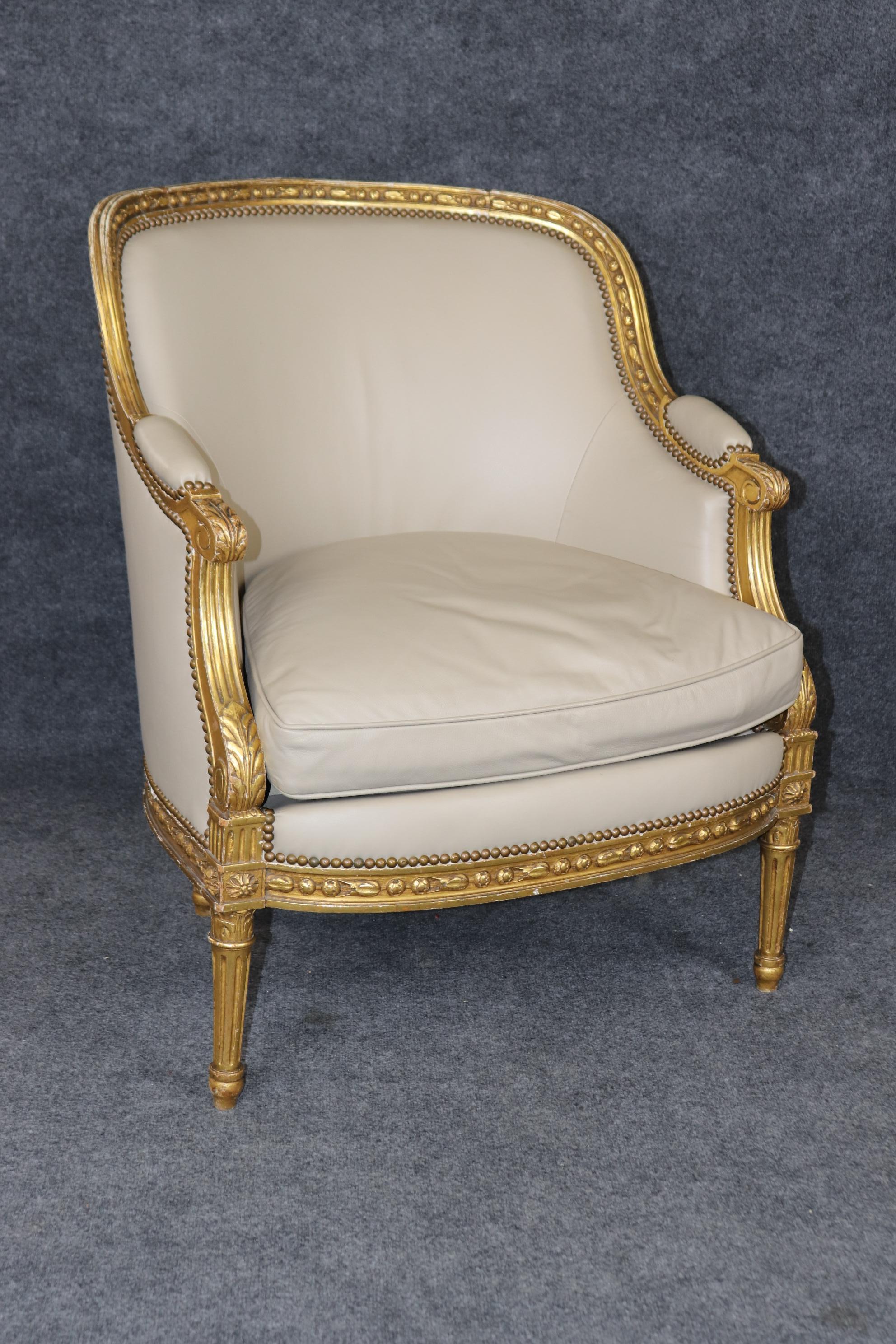This is an incredible NEAR PAIR of companion chairs that were upholstered to look similar in an ivory hued leather upholstery. The chairs are in WATER GILDED finishes and this is known to be the best and most expensive giltwood finishes made. The