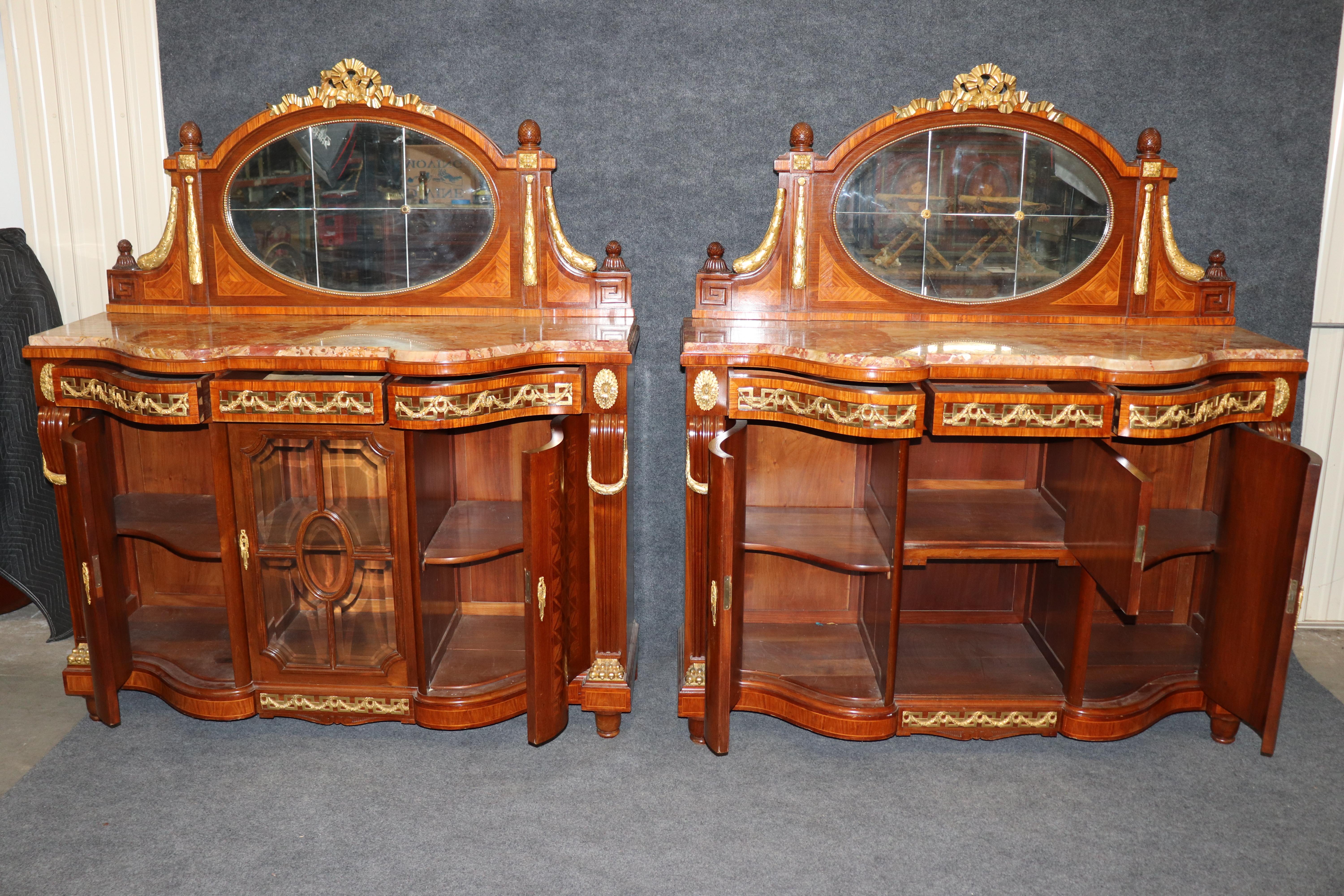 Questa coppia di credenze (o buffet) altamente decorativa e imponente è uno spettacolare esempio di mobile Rococò Revival di alta gamma, probabilmente risalente alla fine del XIX o all'inizio del XX secolo. Con le loro forme sgargianti, il superbo