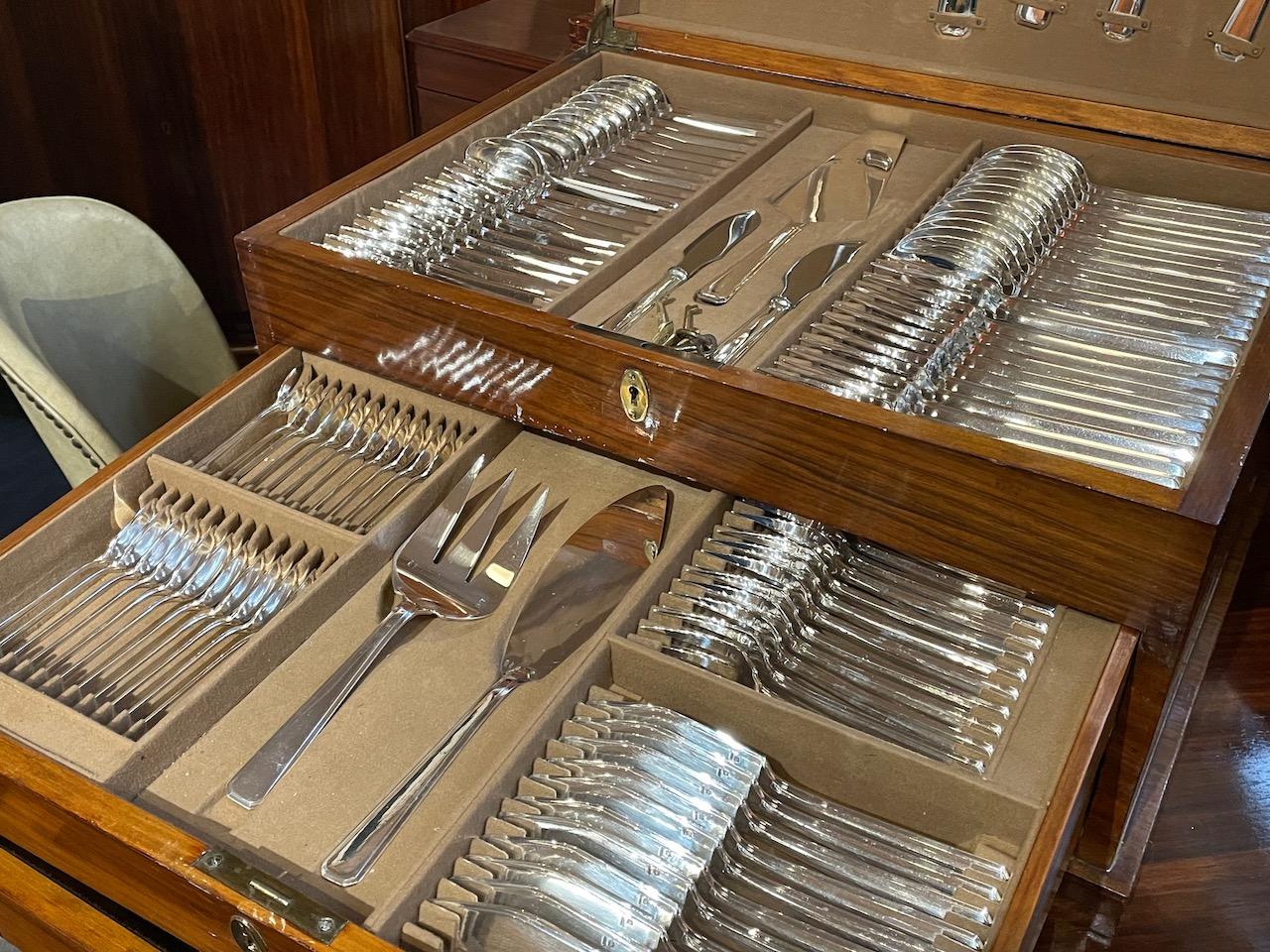 Flawless and complete silver service for 12 with ten pieces in each place setting and twelve unique serving pieces by the French company Ravinet d’Enfert. Nestled in a beautiful wooden silverware chest with a fitted felt lining that holds each piece