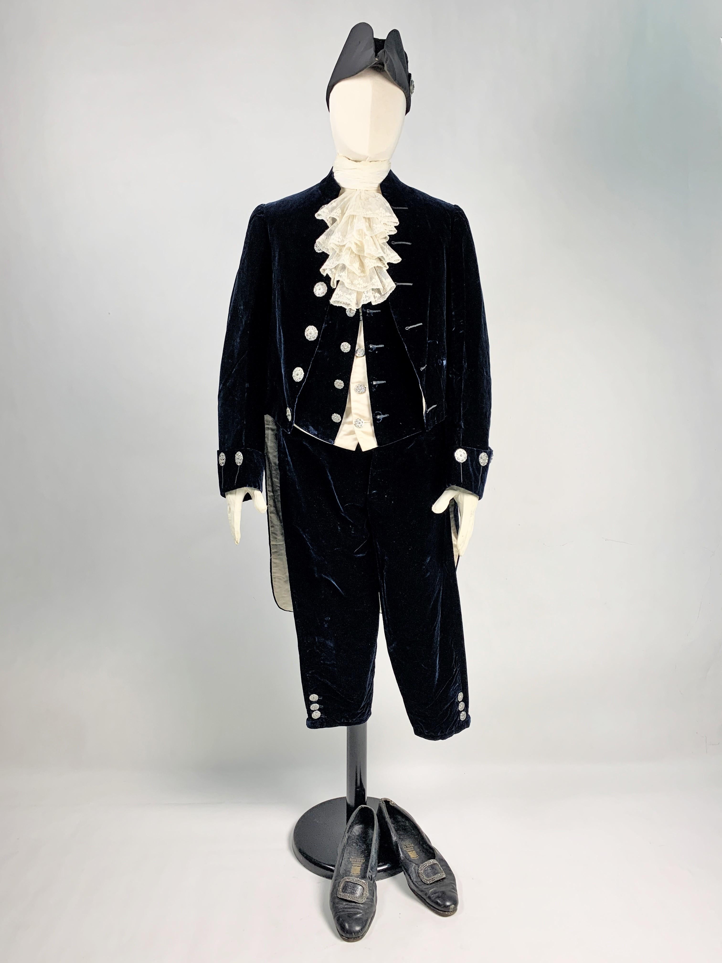 Circa 1910-1930
England
Complete set of a British Monarchy Court suit dating from the first third of the 20th century. Suit, waistcoat and breeches in night-blue cut silk velvet, complete with diamond-tipped faceted steel buttons and fully lined in
