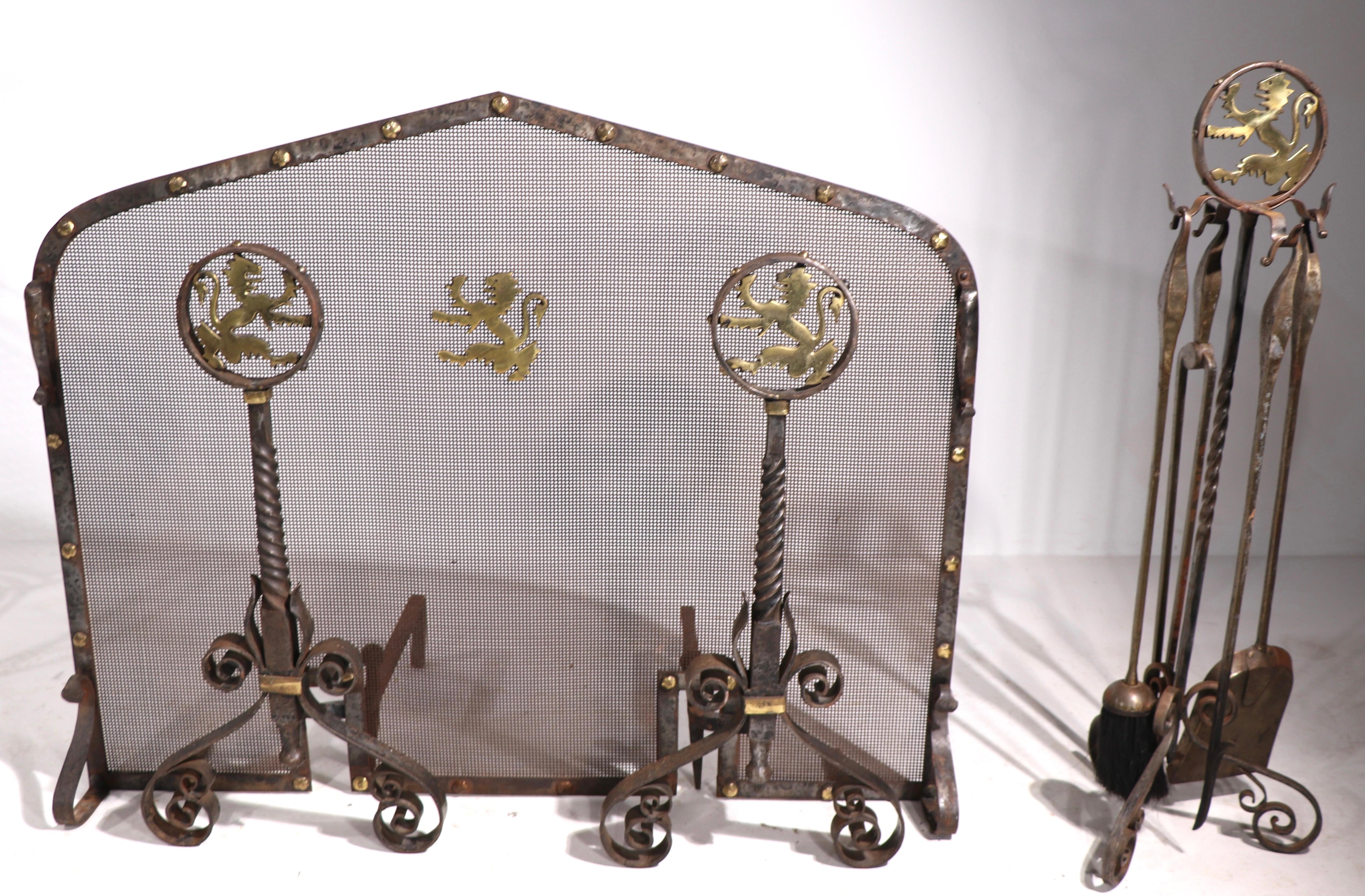 Wonderful Gothic style fireplace set to included andirons, tools, and screen.The metalwork is of hand wrought iron with brass stud decorative trim, and a rampant lion also in brass. High quality craftsmanship, reminiscent of Brant or Bach, unsigned.