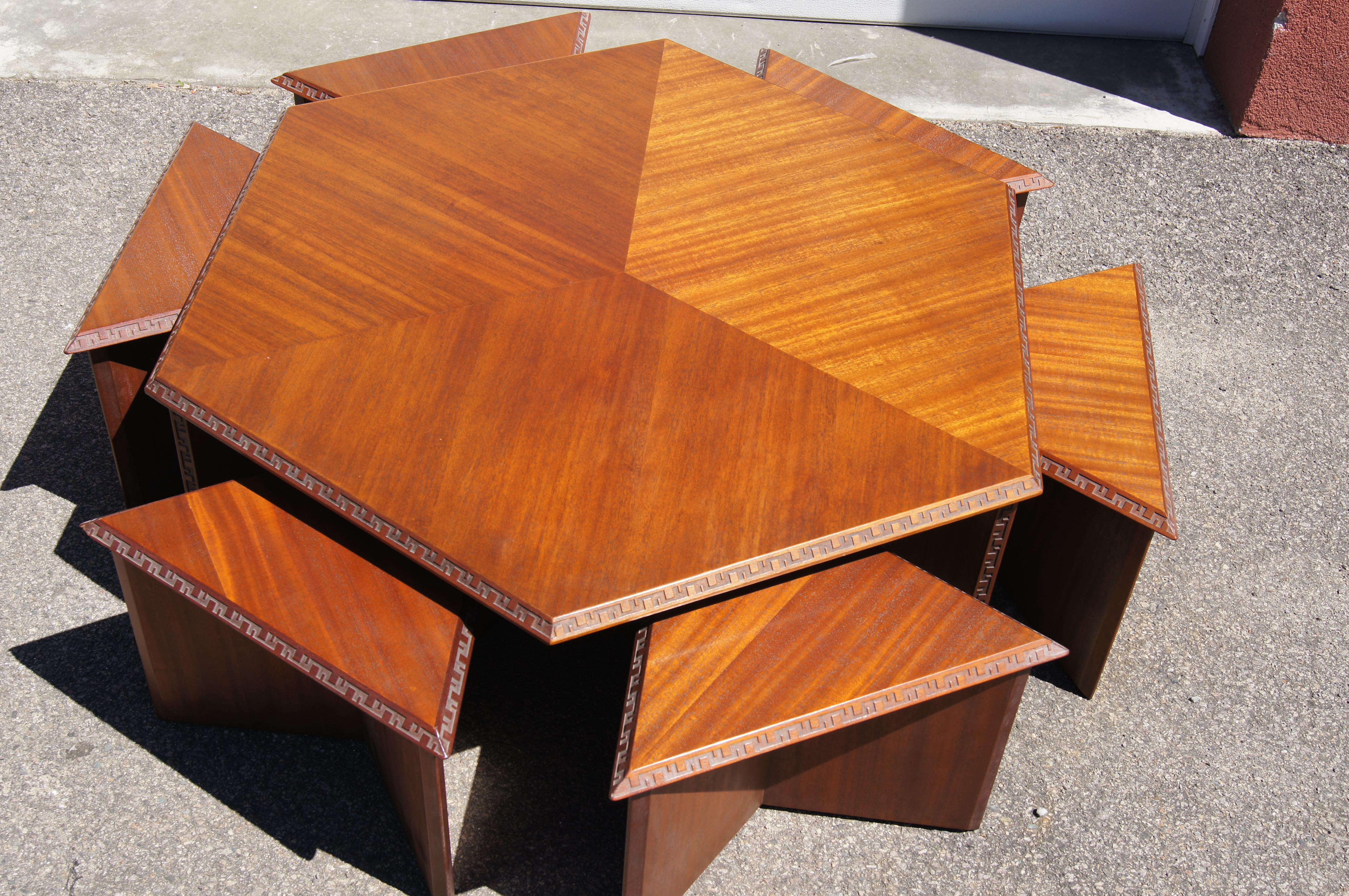 This extraordinary set is part of the Taliesin collection that Frank Lloyd Wright designed for Henredon in 1955. It comprises a mahogany coffee table whose hexagonal top sits on a tripod base and six triangular mahogany stools that slip underneath.