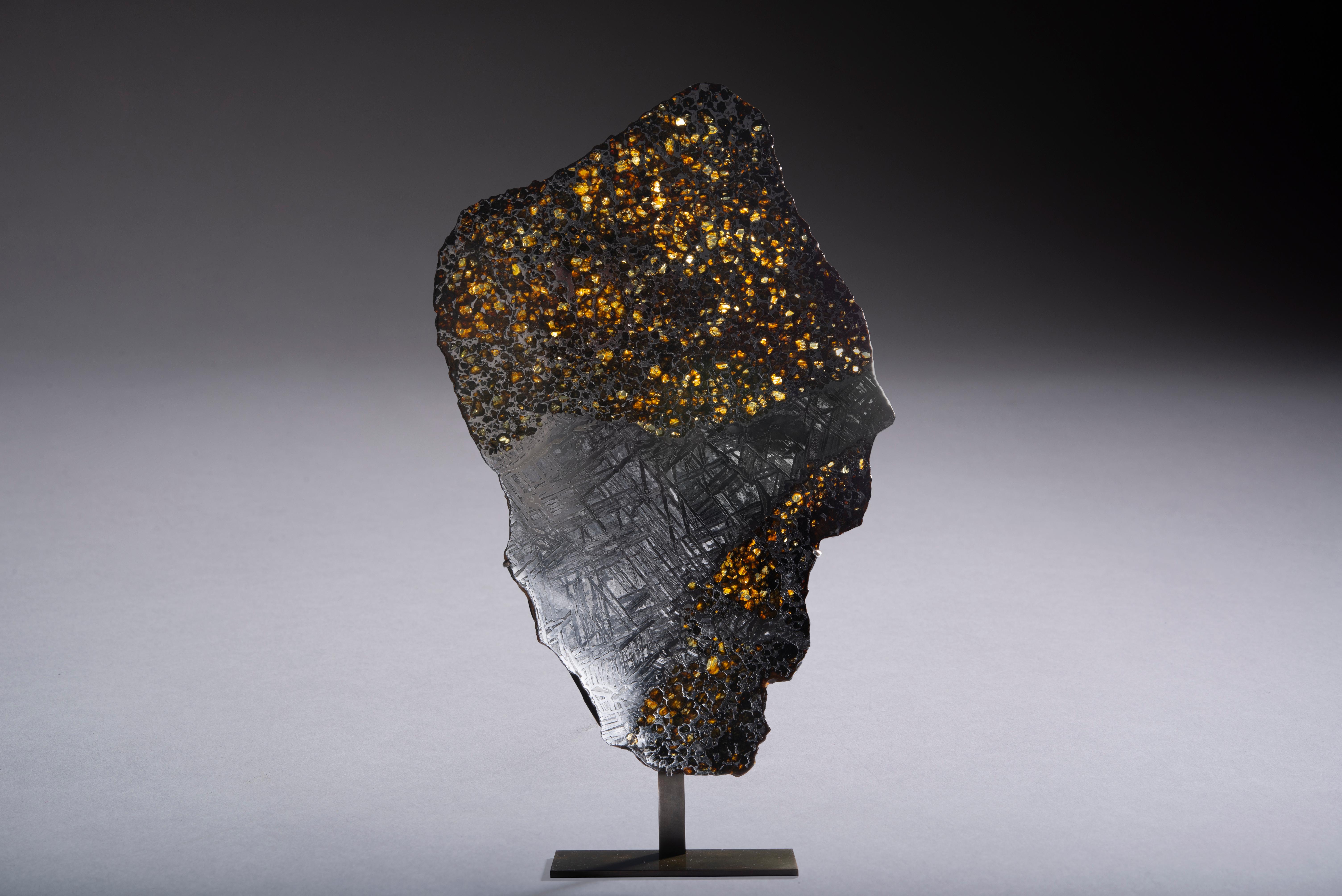A magnificent cross-sectional cut from the pallasite meteorite Seymchan, recovered from the bed of the river Hekandue in the Russian Far East. It has been prepared to reveal the honeycomb-like structure characteristic of pallasites, with gems of