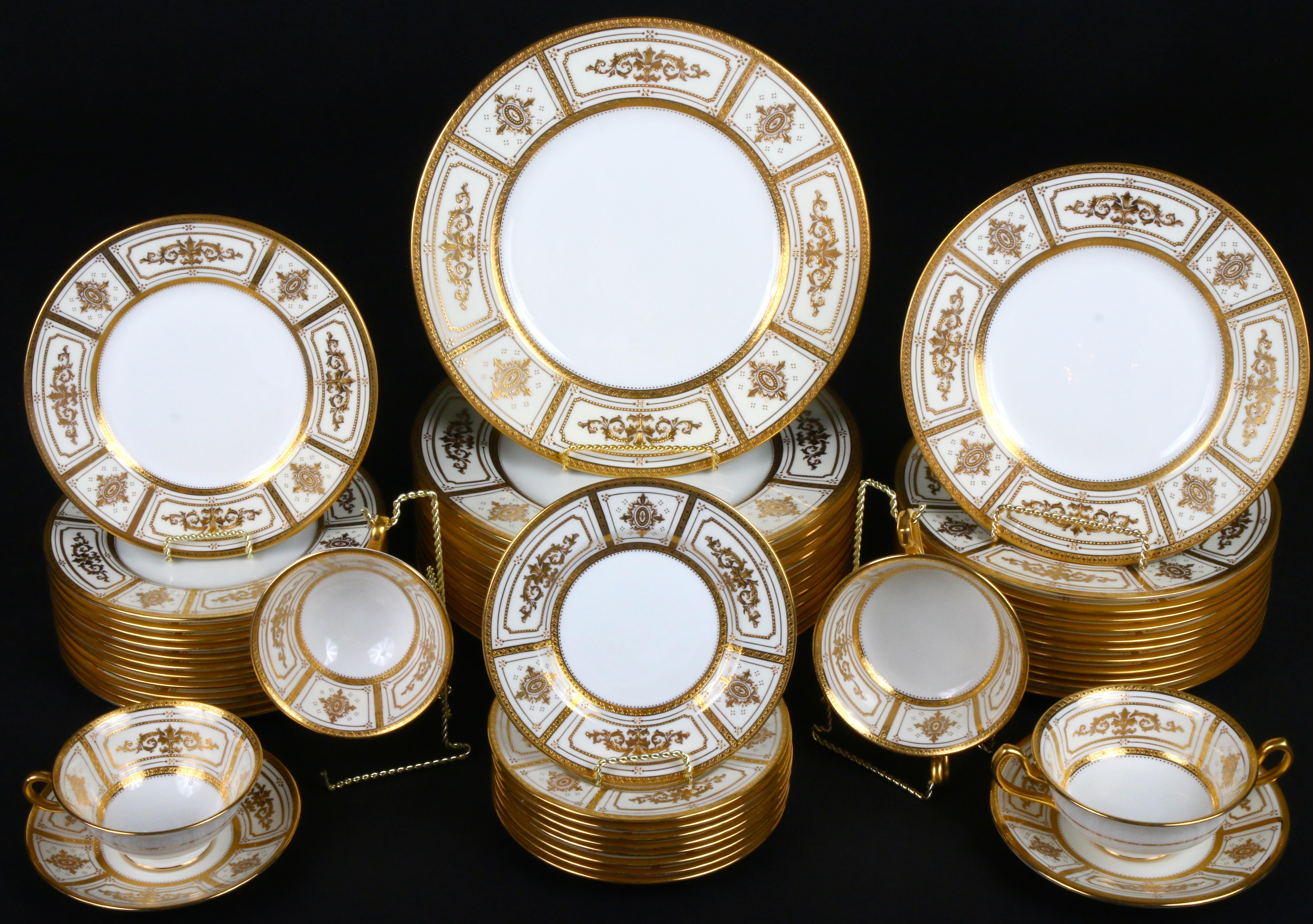 Here is a rare 22-karat gold on ivory ground complete service for 12 from Minton, Stoke-on Trent, England. The set includes dinner, salad, dessert and bread plates, as well as double-handled cream soups with underplates and teacups with saucers. One