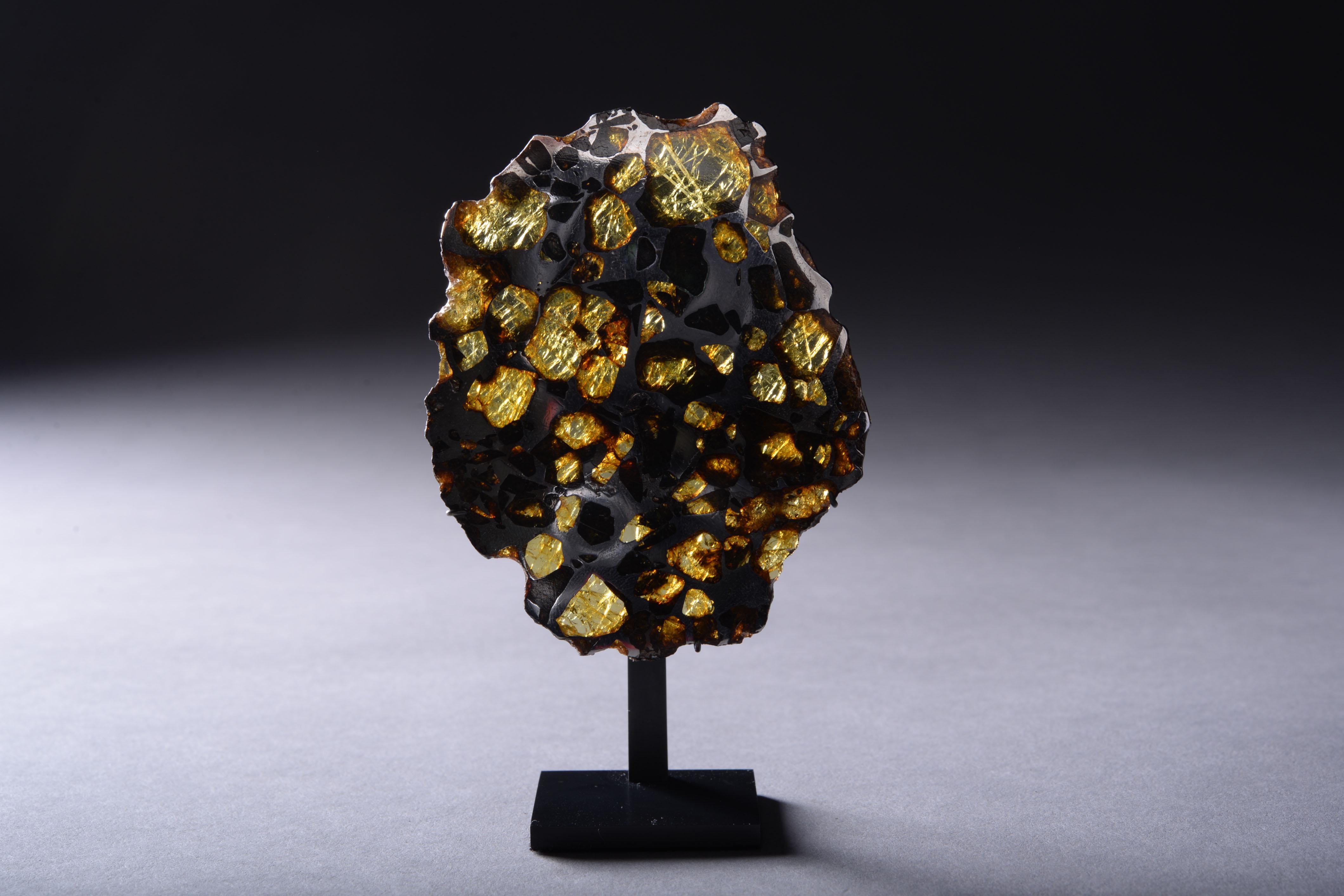 This complete cross-sectional slice from the Imilac meteorite has been prepared to reveal shimmering olivine and peridot gems embedded in an iron-nickel metallic matrix. The magnificent honeycomb pattern shown here is characteristic of pallasite