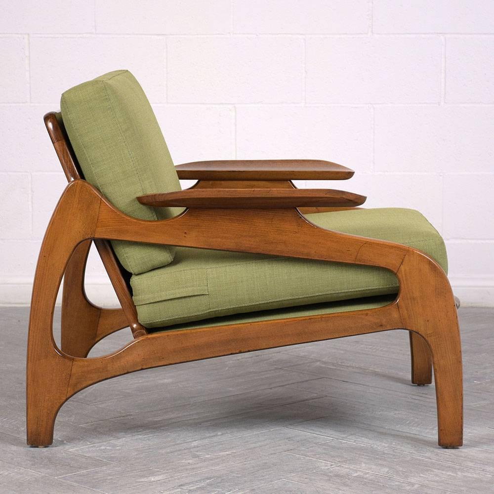 This 1960s Mid-Century Modern lounge chair is designed by Adrian Pearsall and has been completely restored. The geometric walnut wood frame features carved armrests and is stained in a rich walnut color with a lacquered finish. The new, comfortable