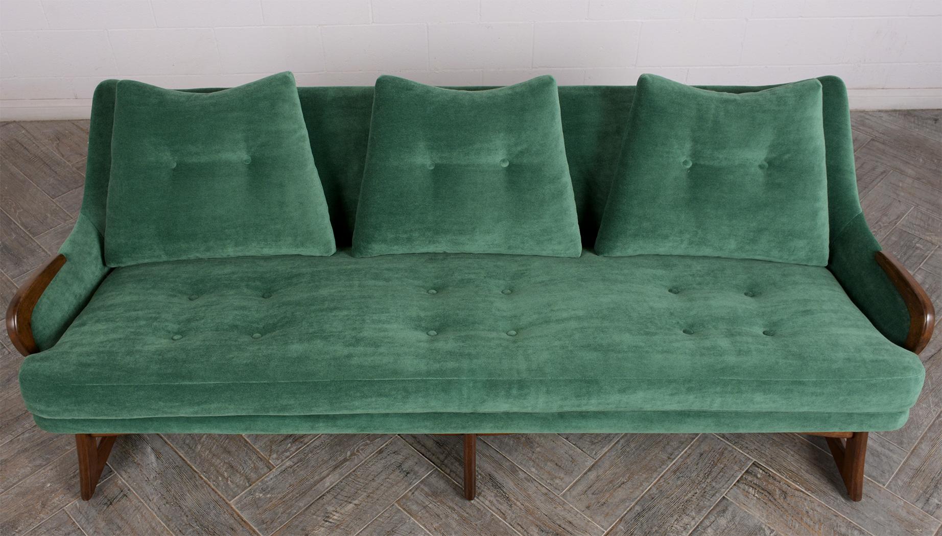This Mid-Century Modern sofa attributed to Adrian Pearsall has been professionally restored and features a unique stylish walnut frame with a newly lacquered finish. The sofa has also been professionally reupholstered in a dark green color velvet