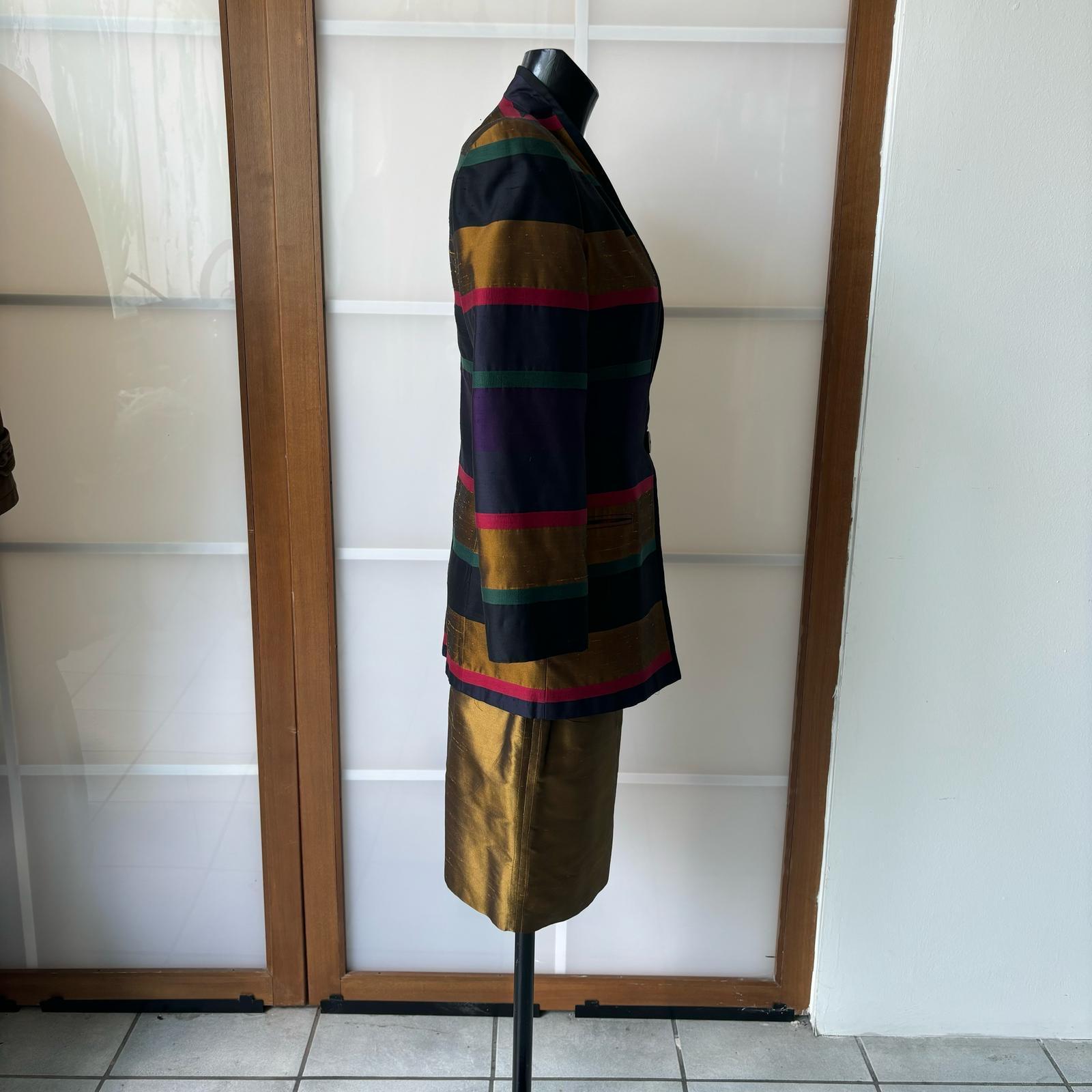 Costume 3 pièces  Veste, jupe et top Gianfranco Ferrè
La veste multicolore à rayures horizontales contraste avec le costume couleur bronze. Etat neuf
Mesures :
Veste - Epaules 44 cm
Manche 58 cm
Longueur 79cm
Haut - Poitrine 52 cm
Longueur 62