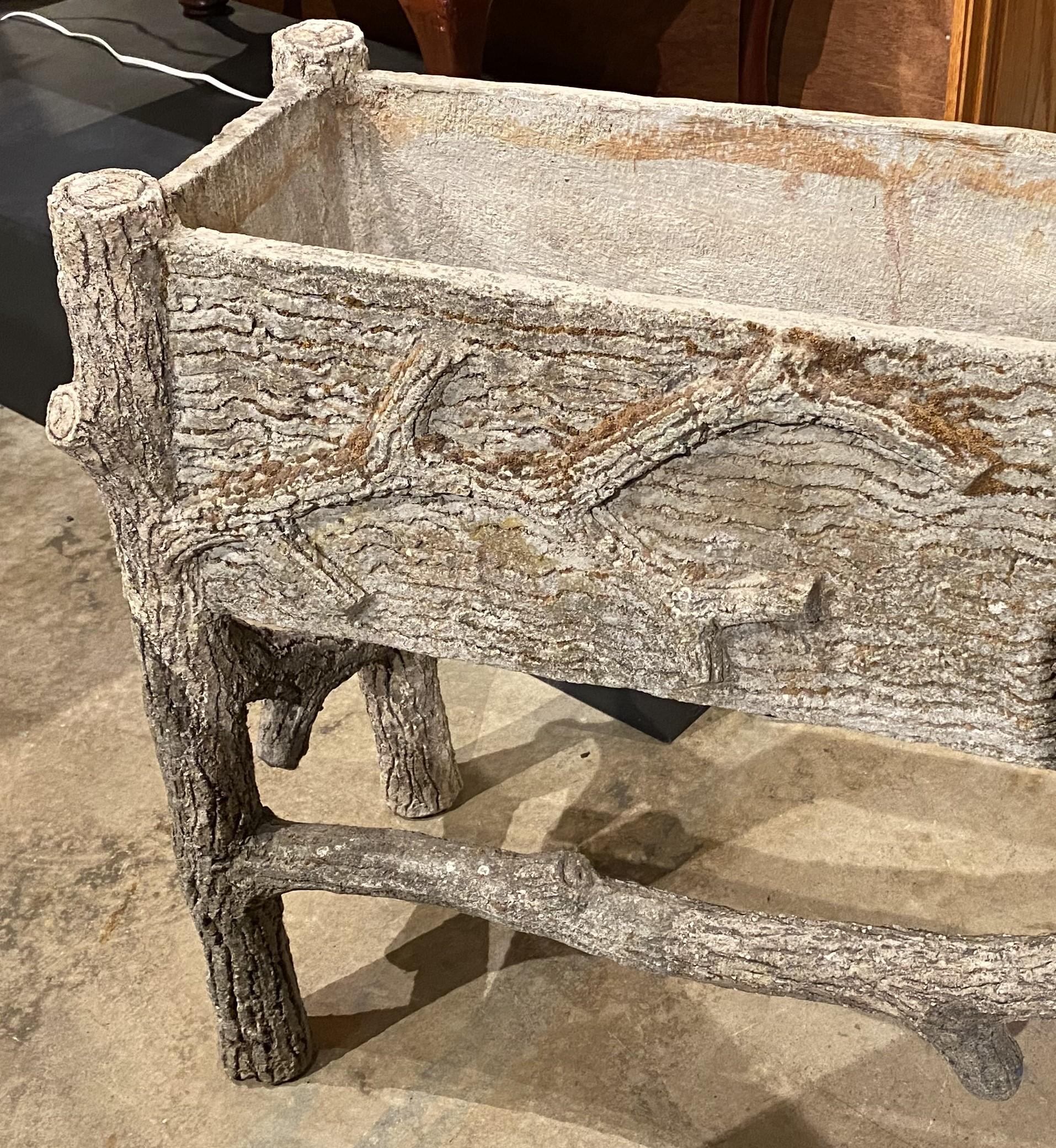 A nicely detailed rectangular faux bois planter in composition stone, with realistic branch detail, dating to the 20th century in very good condition, with minor surface discoloration from moss and exterior use, holes for water drainage, and other