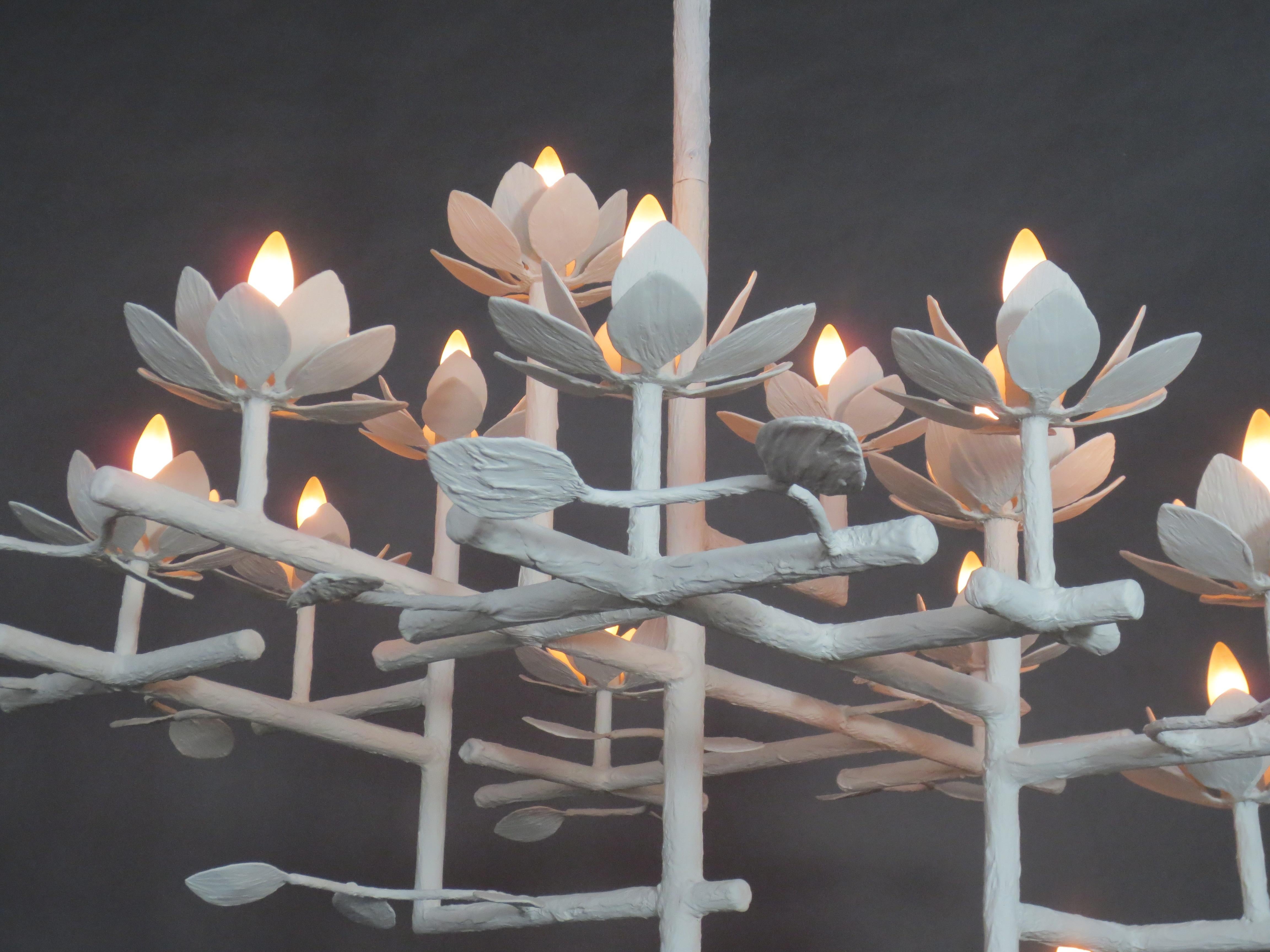 Compressed Lotus plaster chandelier by Tracey Garet of Apsara Interior design.
The Compressed Lotus chandelier has multiple layers and is shown in white plaster. There are 12 lotus flowers and branches throughout. Each flower contains a candelabra