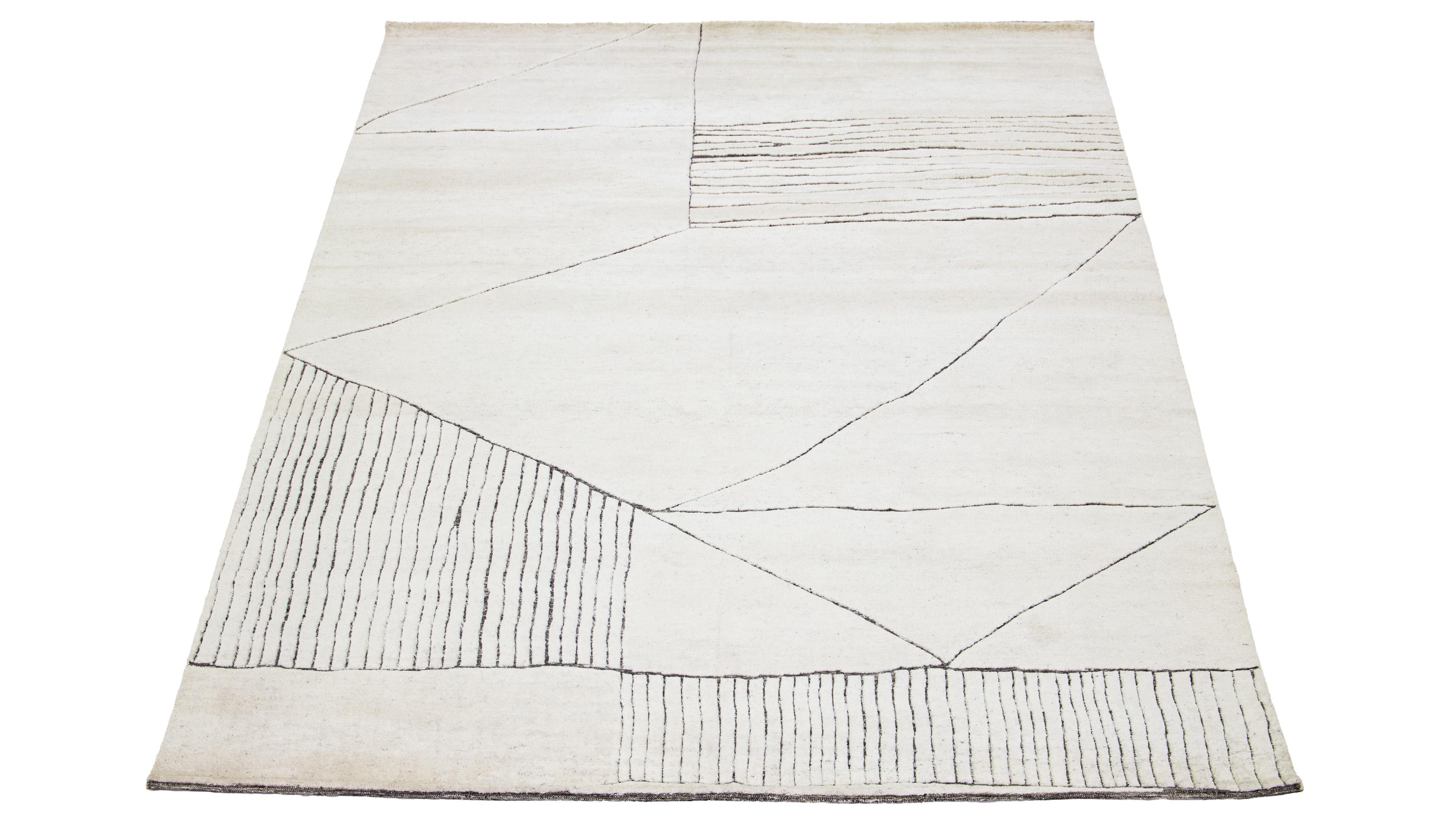 This luxurious wool rug features a timeless Moroccan pattern in a contemporary abstract Minimalist style, utilizing Ivory tones to create a sleek and modern look. It is crafted using traditional hand-knotting techniques, ensuring exceptional quality