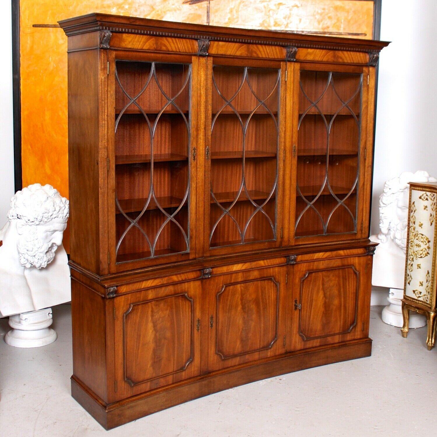 An outstanding mahogany astragal glazed concave bookcase by Bevan Funnel.

The upper section with a flared dentil cornice above marquetry panel frieze, carved scrolling corbels and astragal glazed doors enclosed shelving. The lower section with