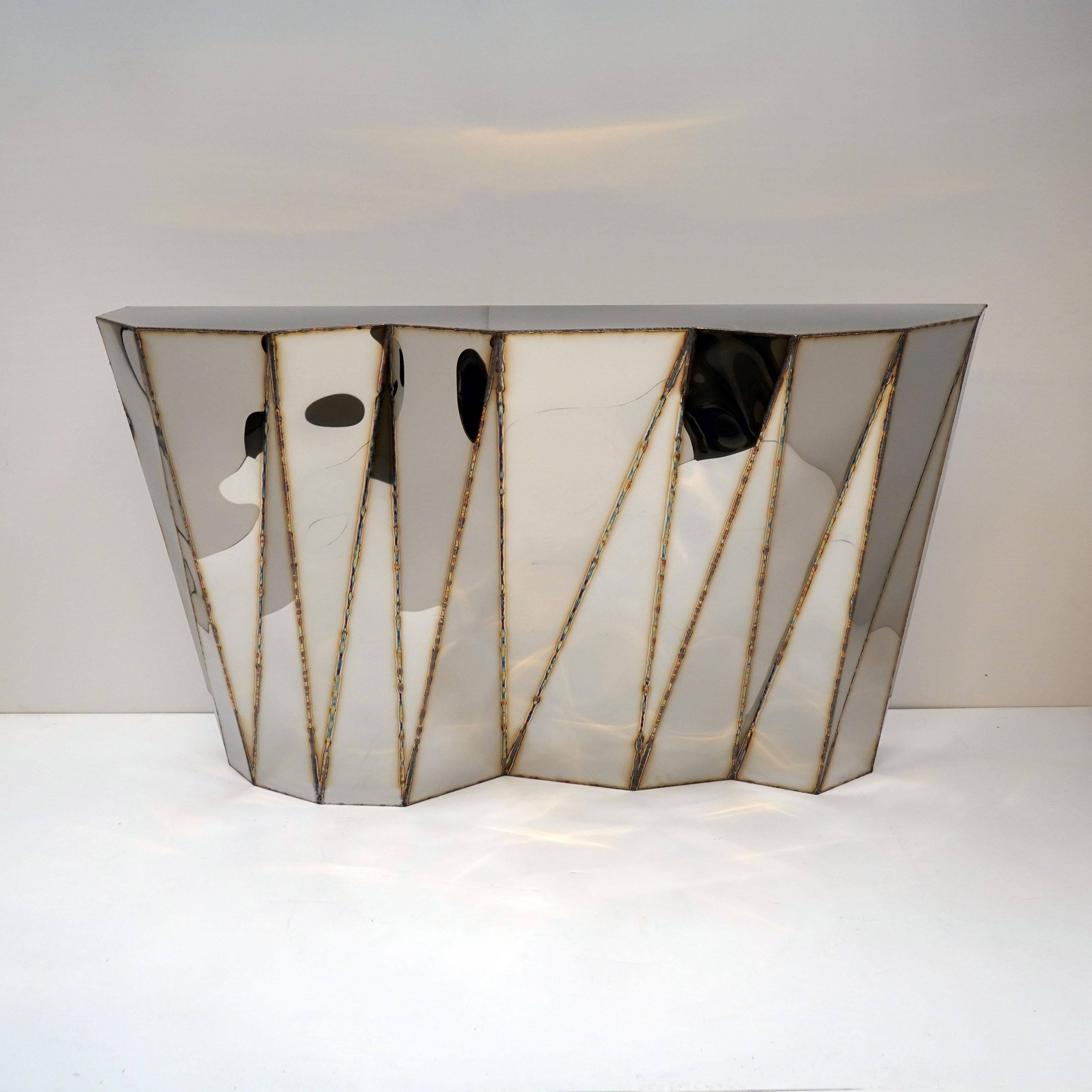 Concertina Console in Welded Mirror-Polished Stainless Steel by Julian Mayor
Limited Edition of 8 + 4AP.
Dimensions: D 43 x W 160 x H 89 cm. 
Materials: Mirror-polished stainless steel.

Julian Mayor is a British artist and designer renowned for his