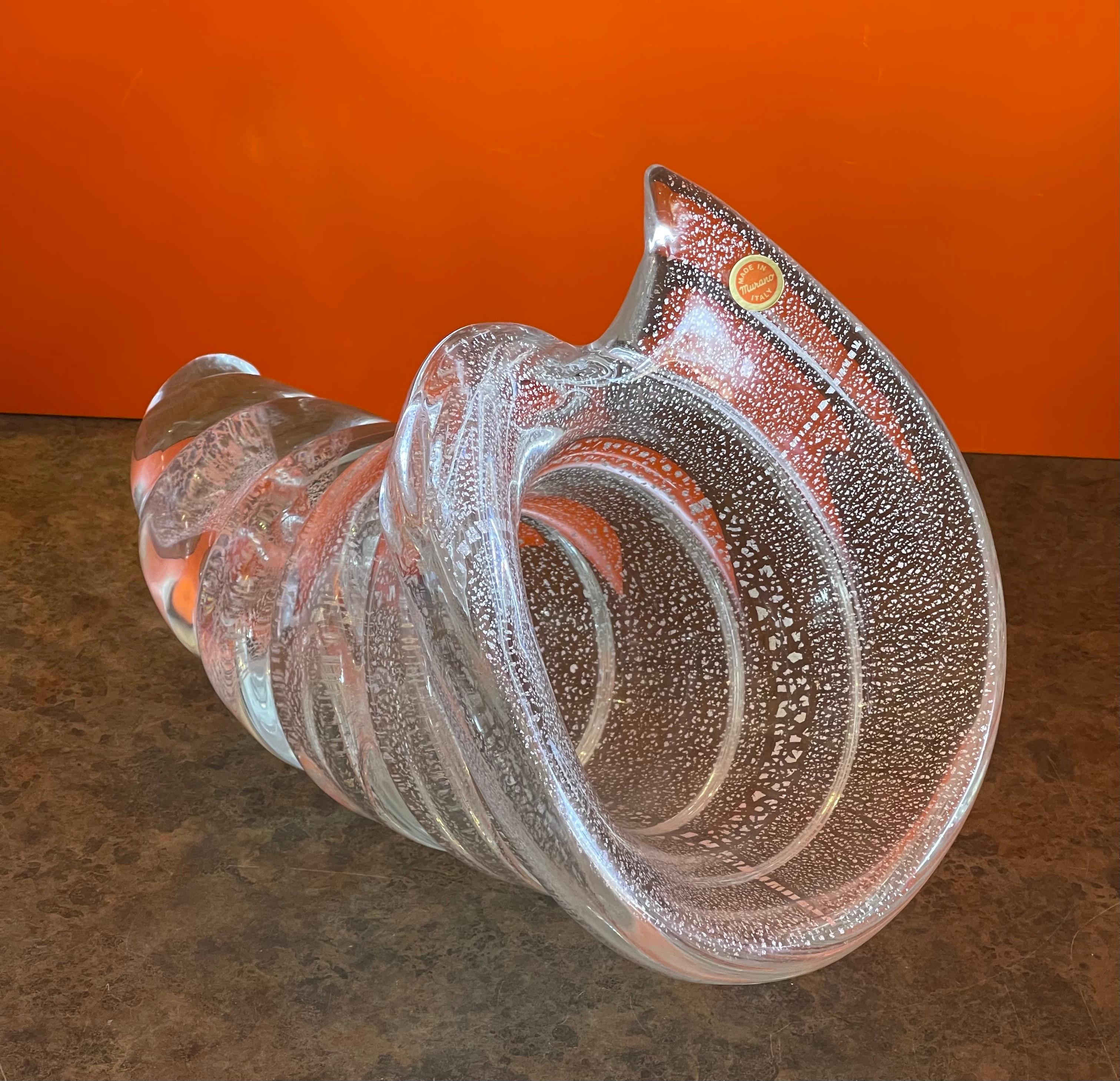 Beautiful conch shell art glass bowl by Glass Studio Murano, circa 1980s. The piece is clear glass with Sommerso white specks and is in excellent condition with no chips or cracks. The bowl is very heavy and signed on the underside 