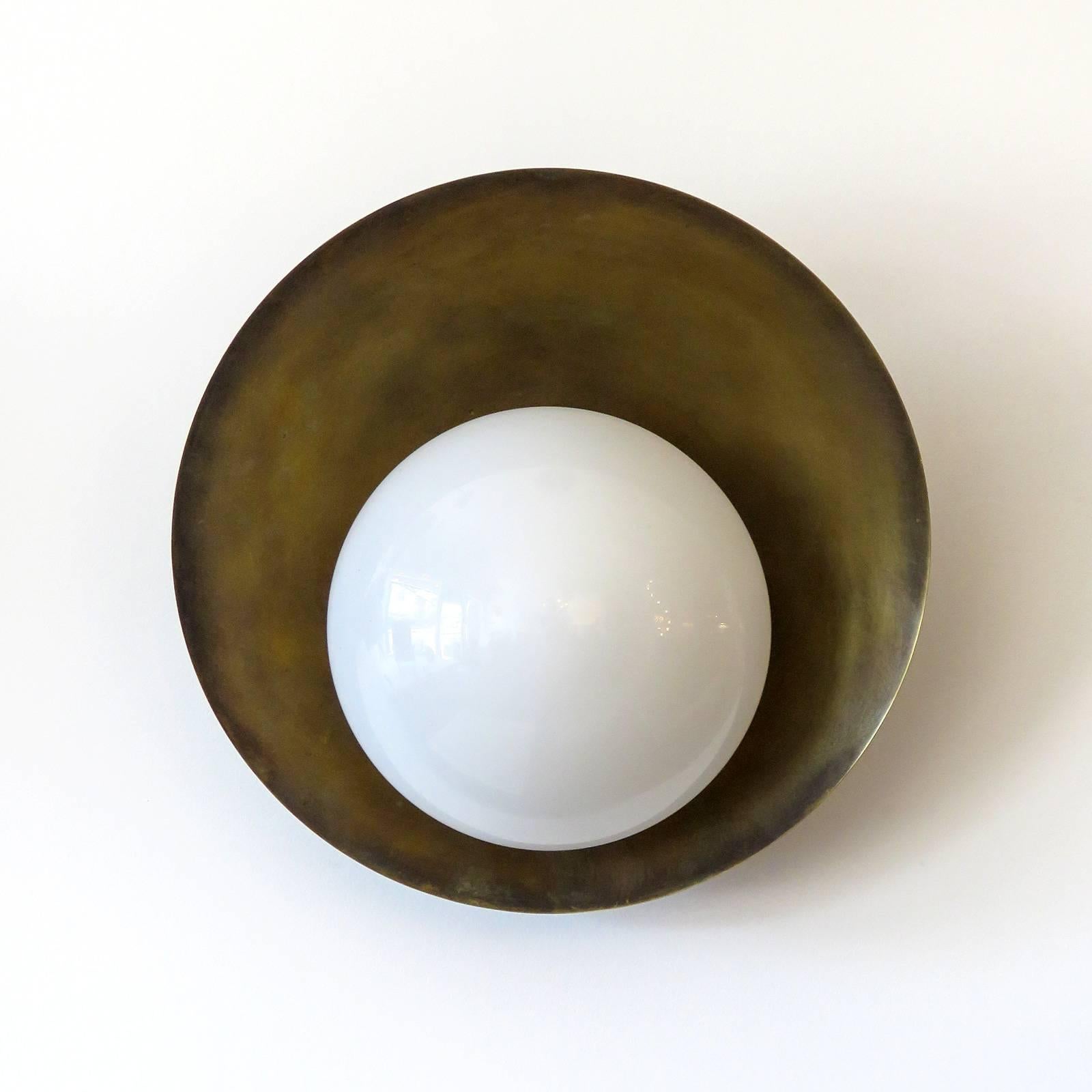 Eleganti lampade da parete per interni/esterni Concha disegnate da Gallery L7, realizzate e rifinite a mano a Los Angeles in ottone americano, con un paralume in vetro opalino (lucido o satinato) su un disco in ottone grezzo invecchiato. Una presa