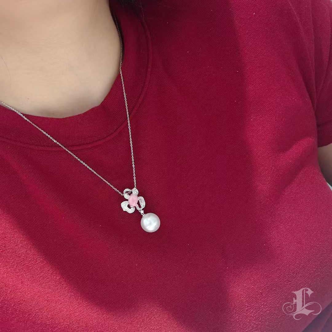 Eine leuchtende Harmonie aus Seltenheit und Eleganz: Dieser Anhänger zeigt eine zartrosa Muschelperle (1,87 ct) mit partiellem Flammenmuster und natürlichen Kalziumeinschlüssen, eingefasst in ein Diamantpavé-Motiv in 2,6 g Platin. Darunter hängt
