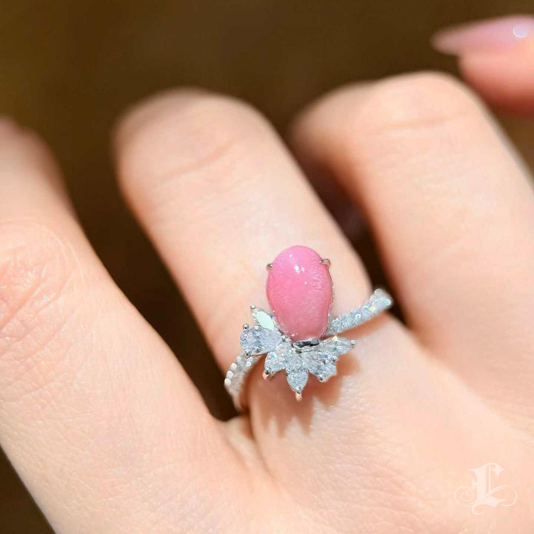 Dalla collezione Conchéa, una celebrazione dei tesori più rari della natura.
Questo squisito anello è incentrato su una perla conchiglia naturale da 2,63 carati di colore rosa fenicottero, che mostra un motivo a fiamma completamente sviluppato sulla