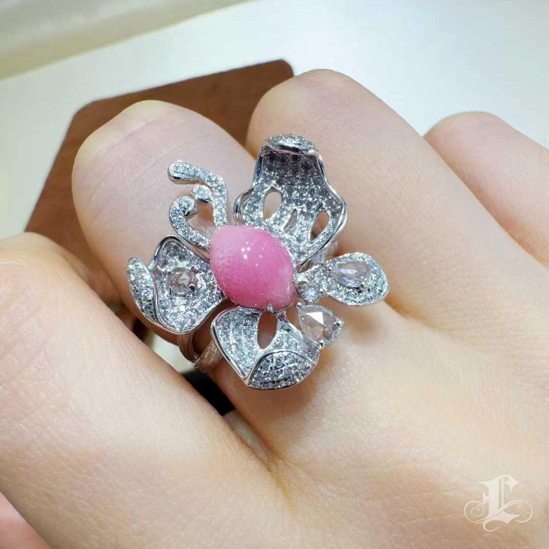 Una dichiarazione di rarità e maestria, questo anello a farfalla presenta una perla conchiglia naturale da 2,3 carati che risplende in una dolce tonalità rosa fenicottero. La perla rivela il suo caratteristico motivo a fiamma - un effetto ottico