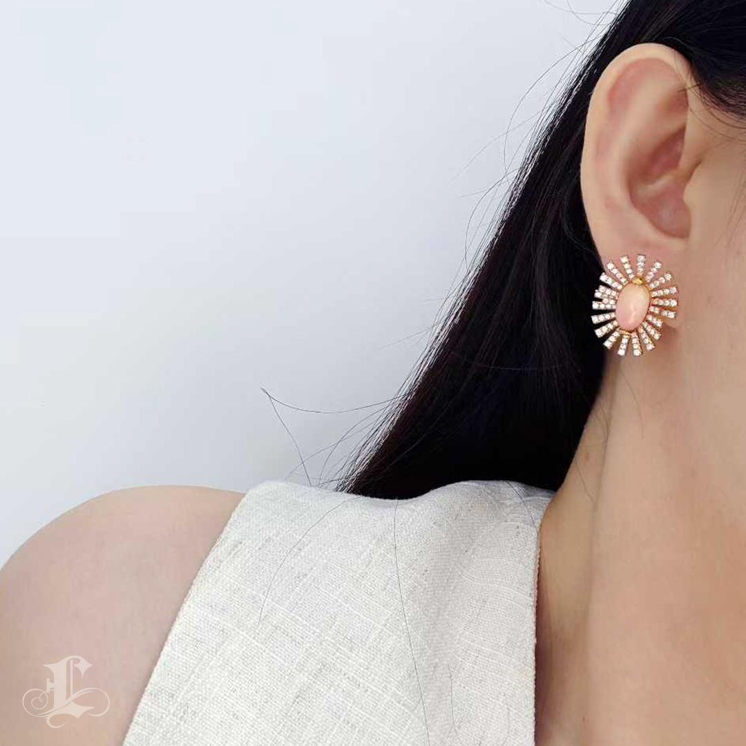 Au centre de chaque pièce se trouve une perle de conque rose saumon - une paire assortie de 8,3ct - avec des motifs de flammes vives et des contours ovales parfaitement lisses. Les perles sont entourées d'une gerbe architecturale de diamants pavés