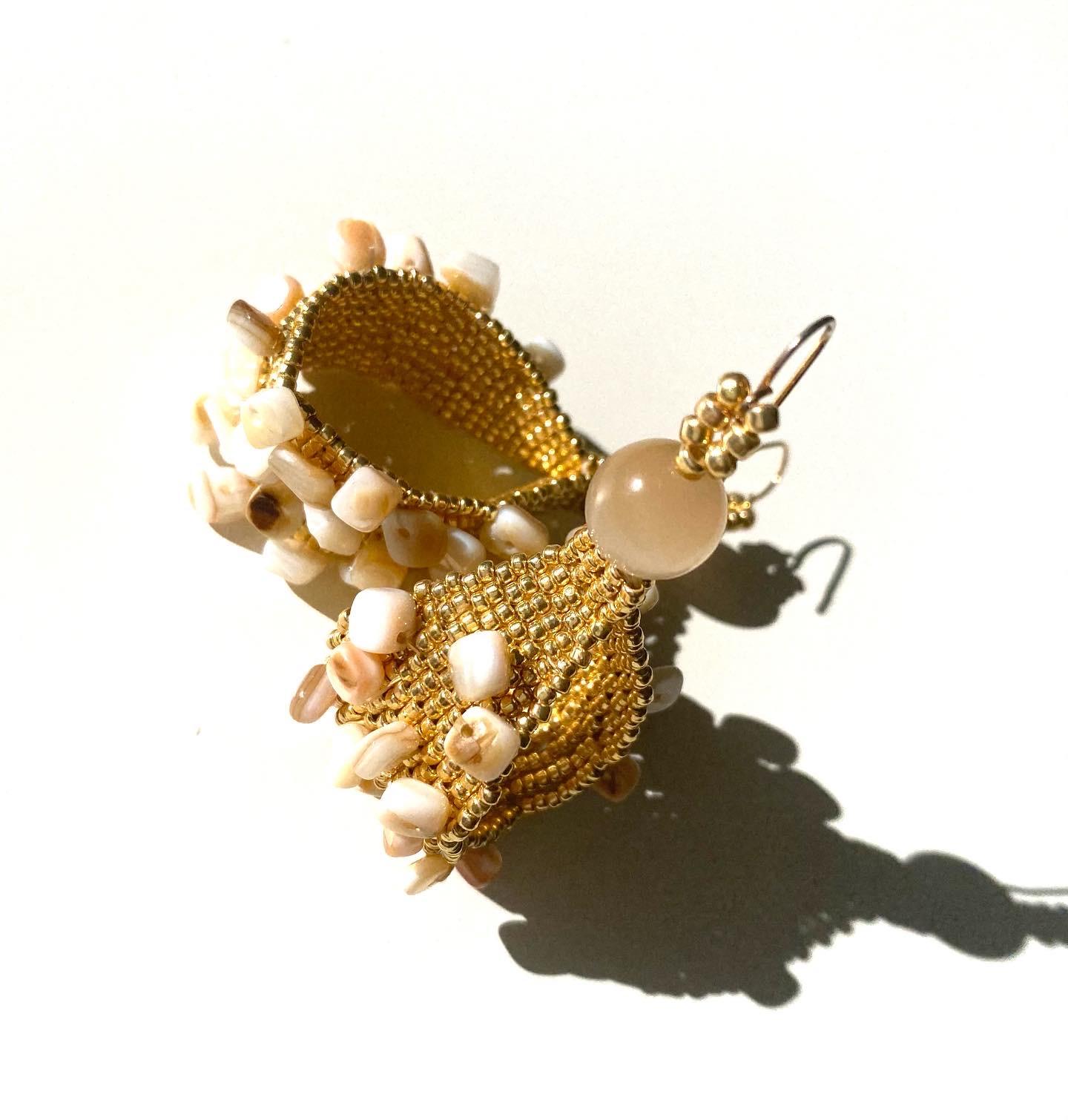 Handwoven permanent 14k gold plated seed beads in wide loop form embroidered with numerous conch shell beads and cats eye glass beads. Inspired by the golden sandy beaches of the Caribbean and the natural treasures that lay upon it.  Conchita hoop