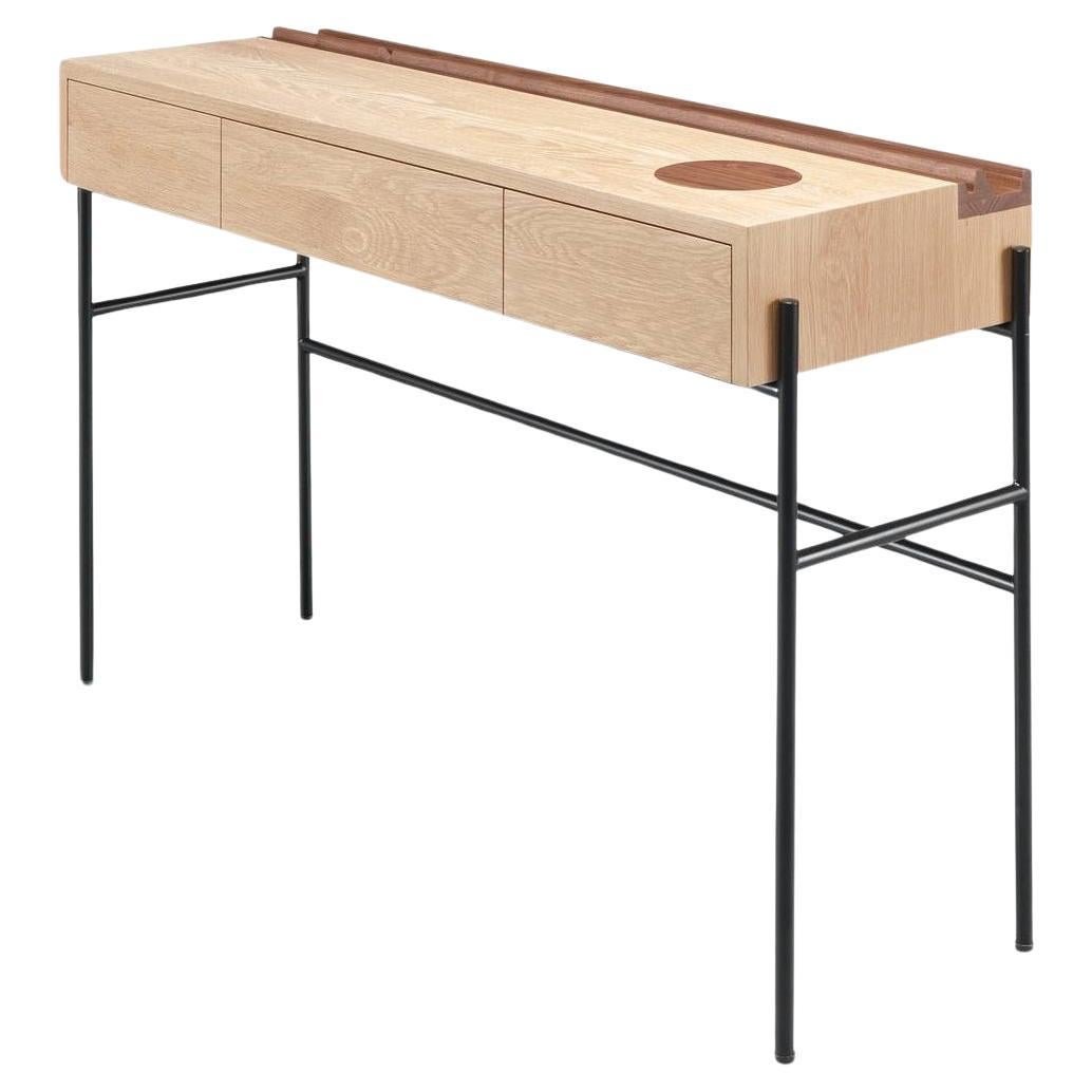 Questa consolle minimalista è meticolosamente realizzata in rovere massiccio, con dettagli in noce. La fusione di elementi in legno e acciaio verniciato a polvere crea un equilibrio armonioso. Semplice, funzionale e poco ingombrante, si integra