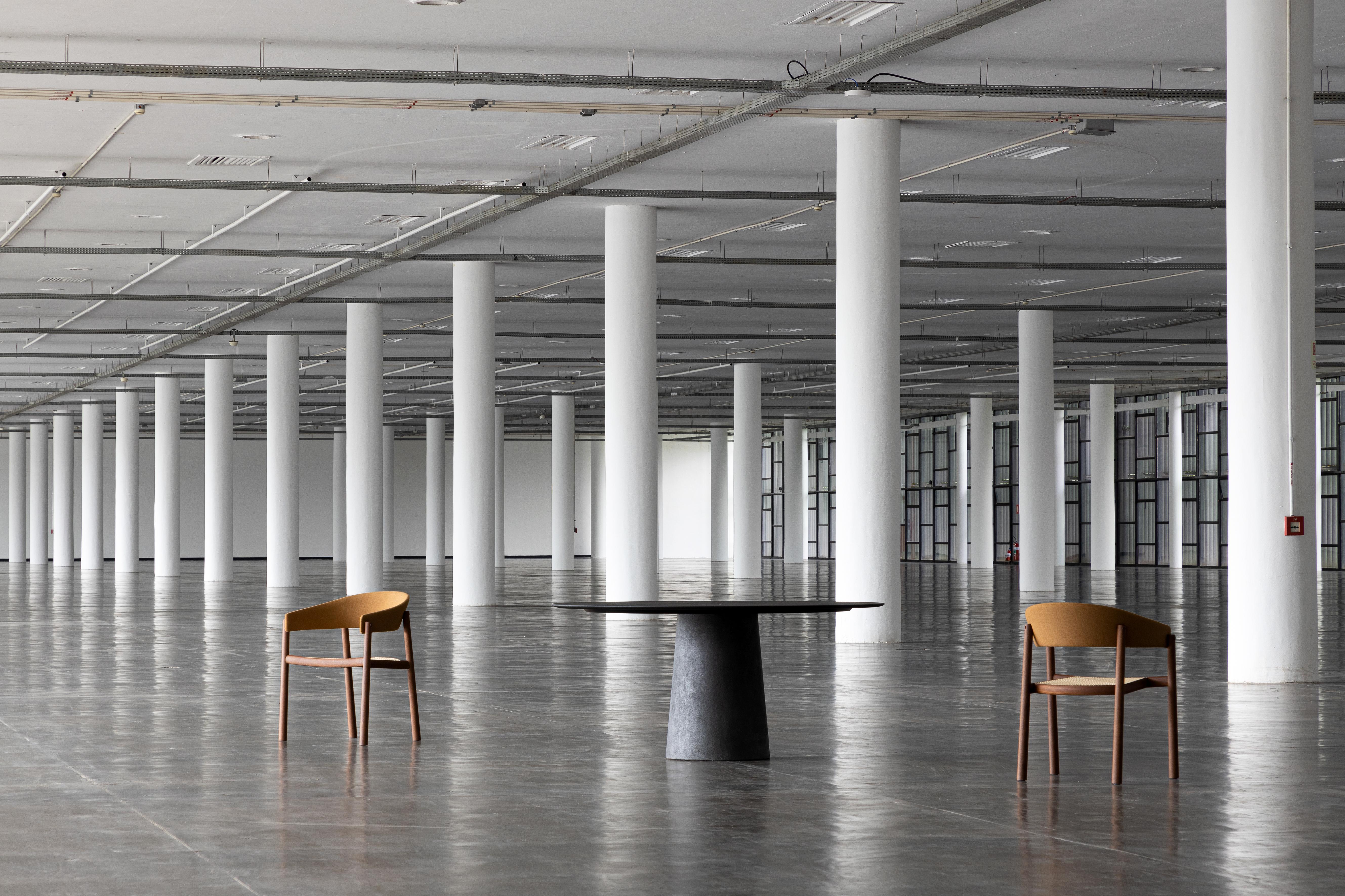 La série Concreta, conçue par ,Ovo, est une remarquable collection de tables qui associe harmonieusement des bases en béton pigmenté à d'élégants plateaux en pierre. Le design se distingue par son essence sculpturale, obtenue grâce au contraste