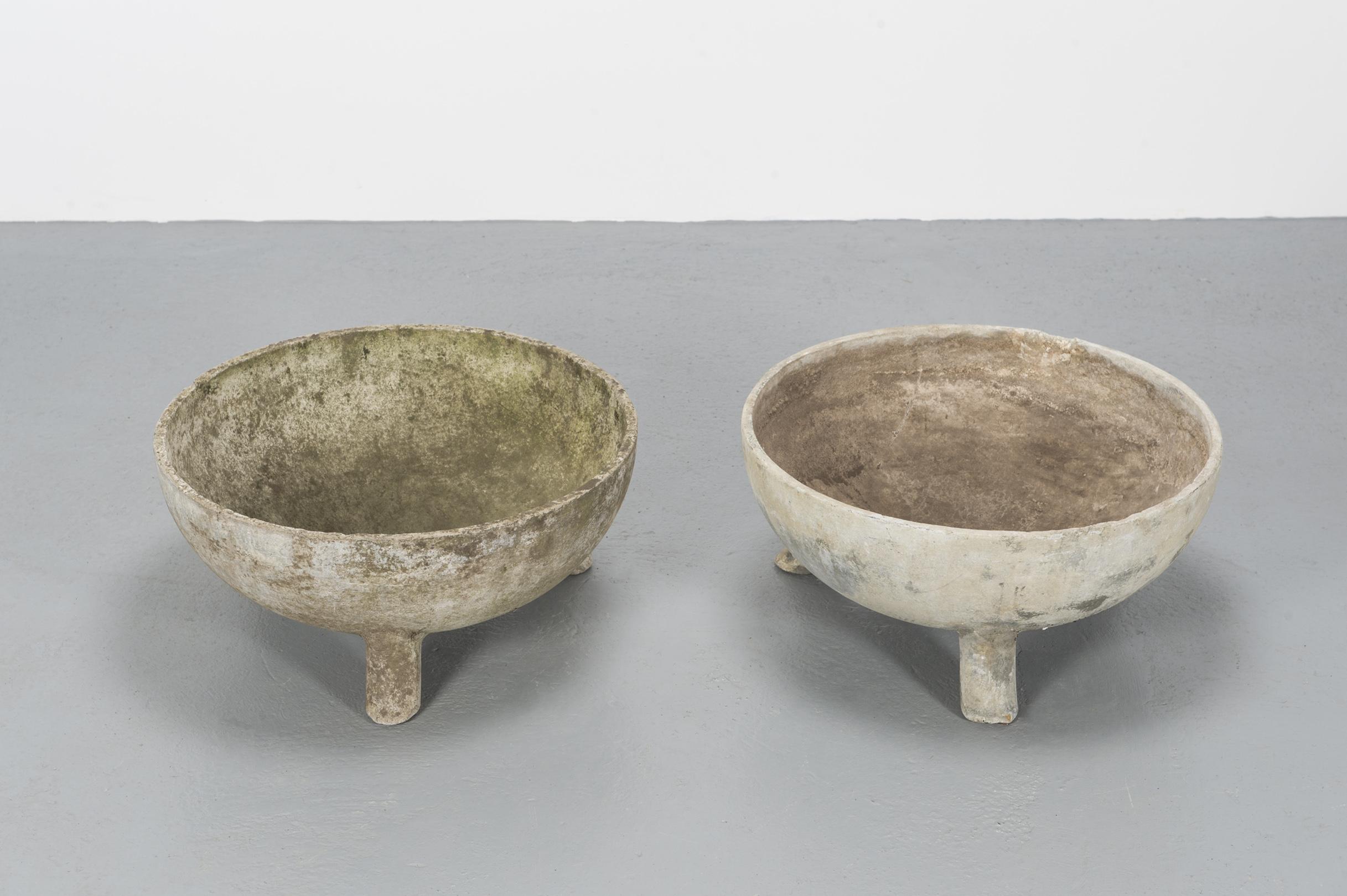 A set of two round large concrete planters in the shape of half bowls, sustained by 3 legs in concrete that lifts them from the ground, protecting the base from deformation and wear.
Very good vintage condition.