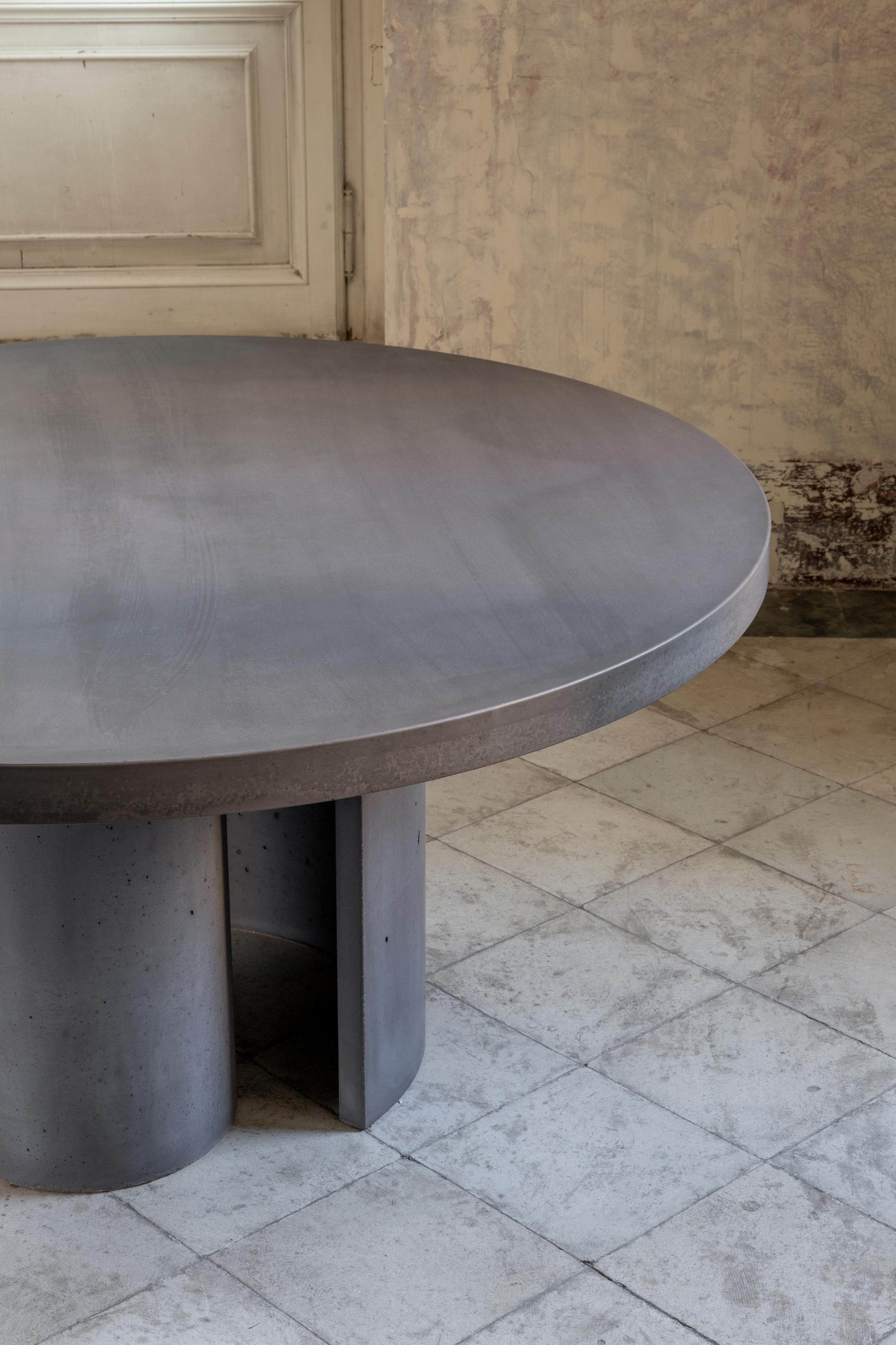 Atlante ist ein runder Esstisch mit essentiellen Linien und einer starken Inspiration. 
Dieser Tisch, der von einem Team erfahrener Handwerker vollständig aus UHPC-Betonmörtel gefertigt wurde, verkörpert perfekt die Werte der Euclide Collection'S,