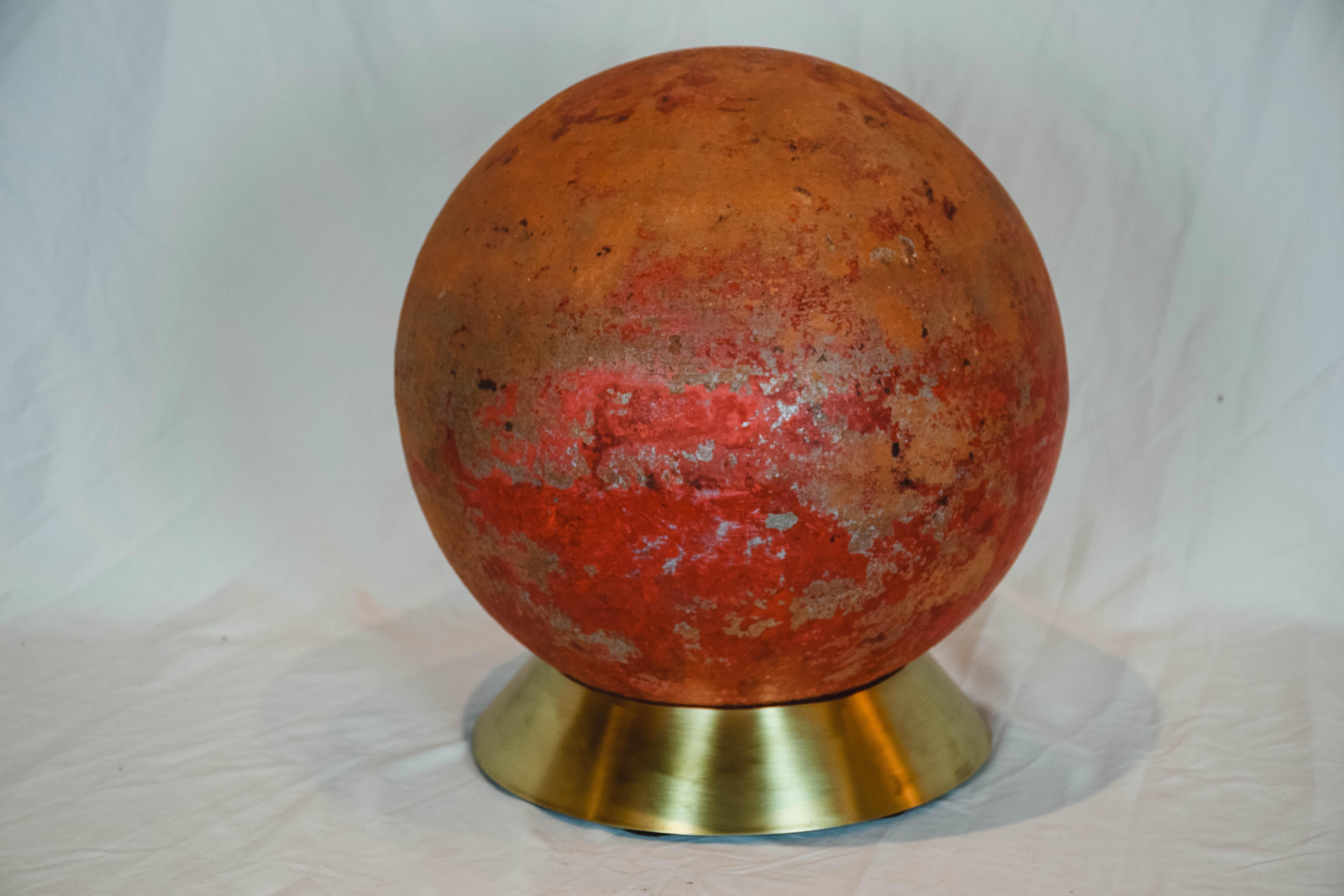 This concrete garden ball on brass base has a beautiful weathered painted red surface, offers a simple, albeit exciting, accessory that is suitable for indoors or outdoors. Any space can be transformed with this garden ball to add a dot of color. We