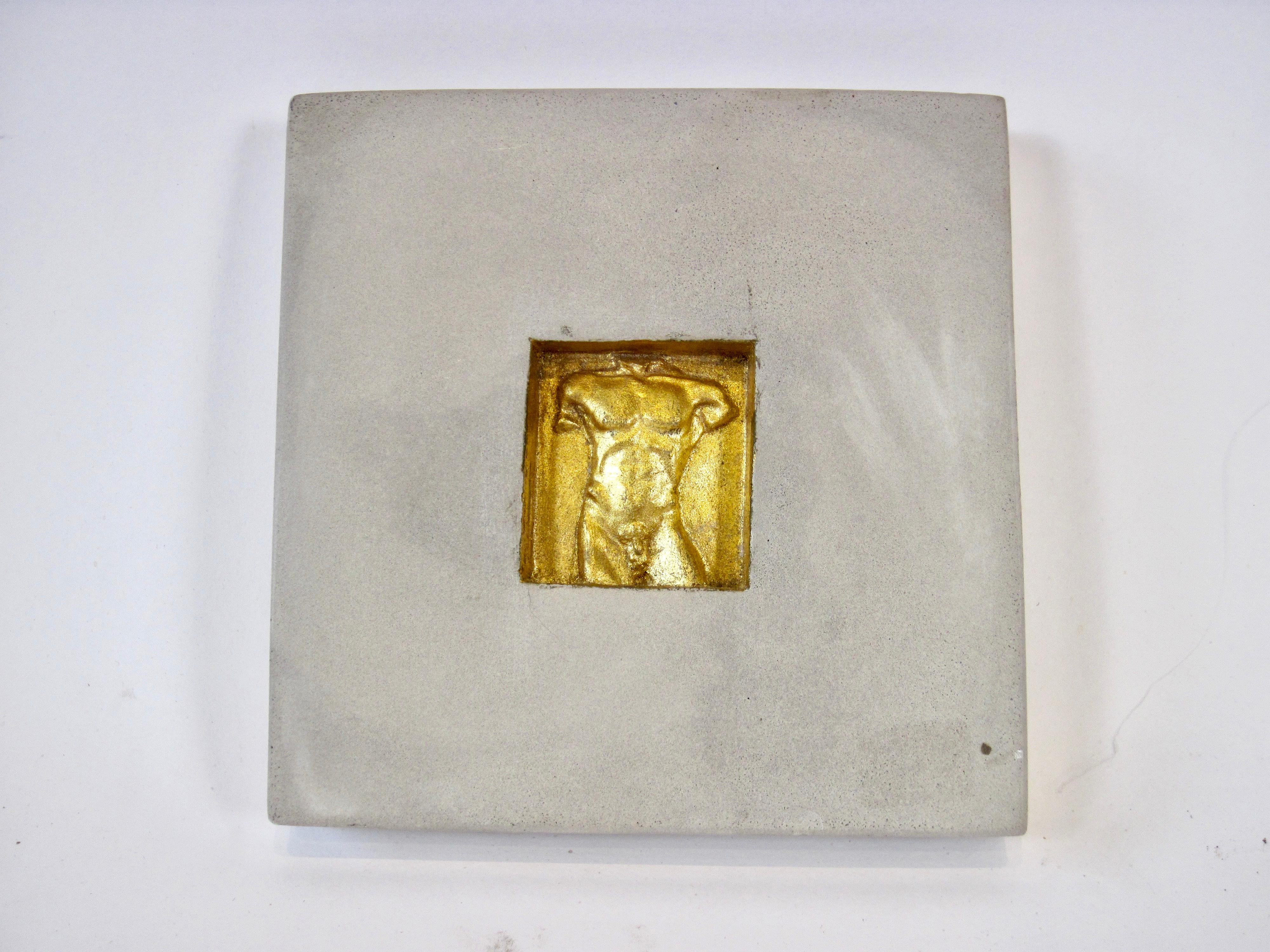 A concrete square tile with a male torso gilt relief design within a center square.  Hand signed by the artist, © MarCo on bottom side edge with a hole  for mounting on reverse. The tiles have both a minimalist vibe by way of the concrete and a