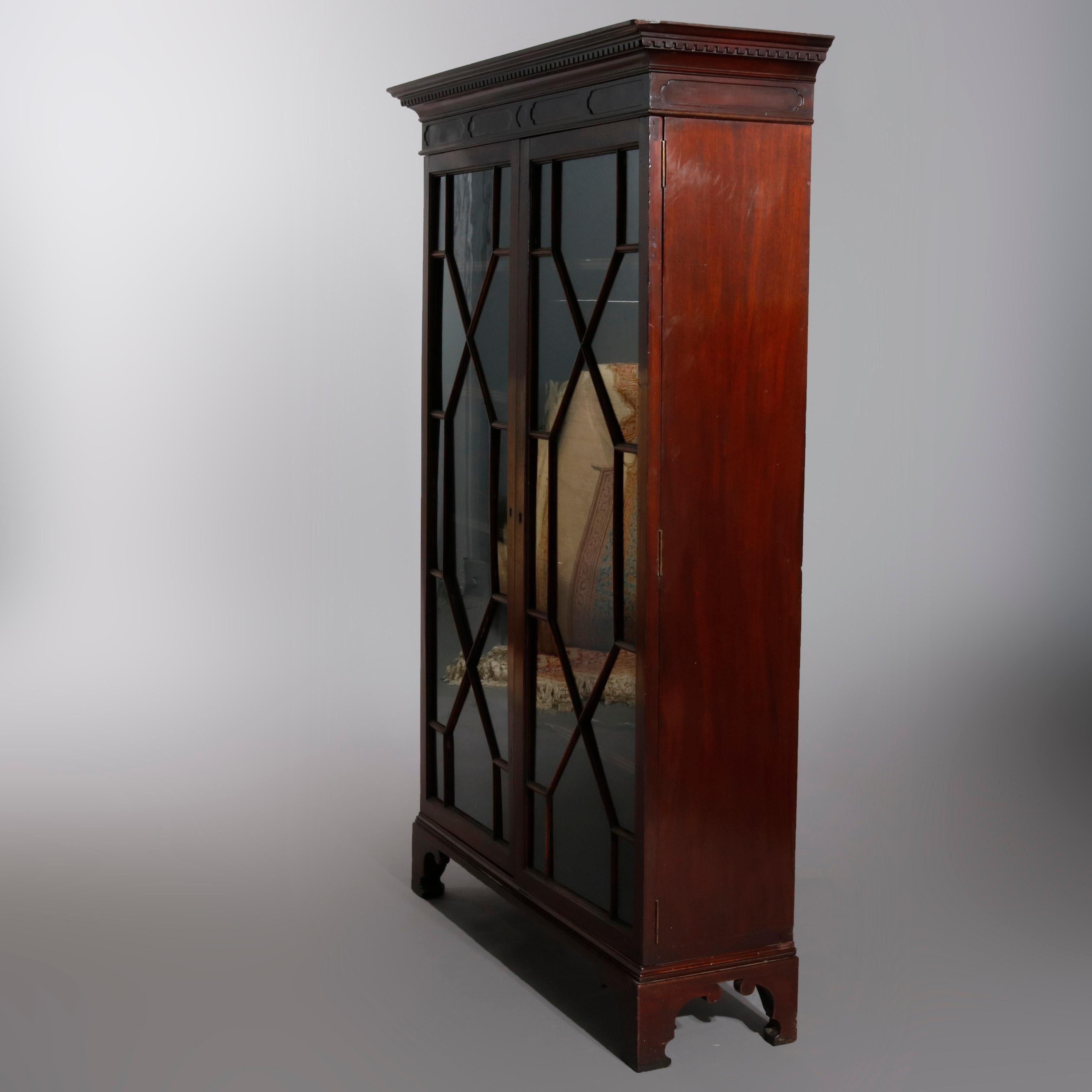 An antique English Georgian bookcase offers mahogany construction with case having dental frieze over double mullioned glass doors opening to adjustable shelf interior, raised on bracket feet, circa 1810.

Measures: 58.25