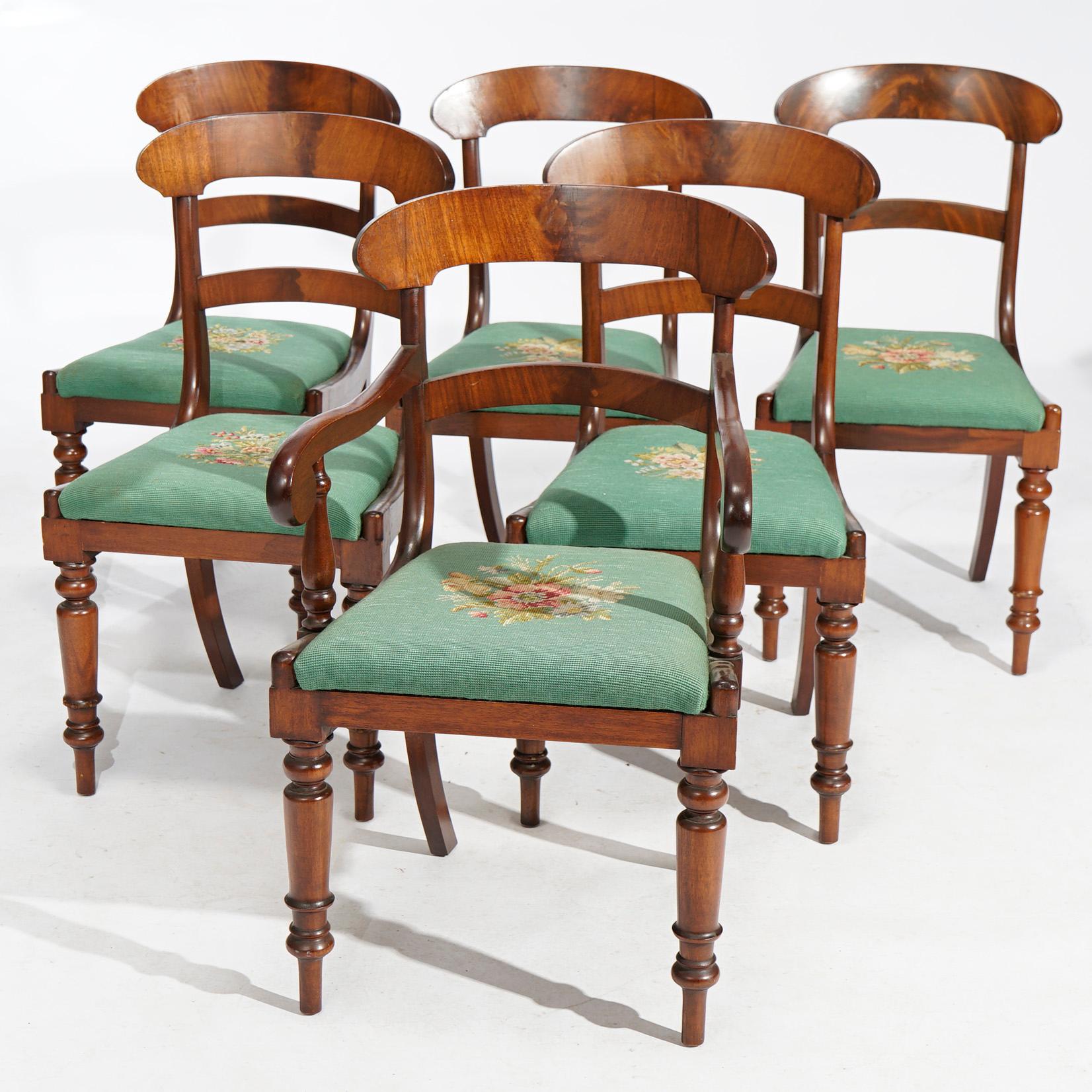 An antique set of six Sheraton dining chairs offer flame mahogany construction with shaped rails, scroll form arms, turned front legs and floral needlepoint seats, c1830

Measure - Armchair 34'' H x 20'' W x 19'' D; Side chairs 34.25'' H x 17.75'' W