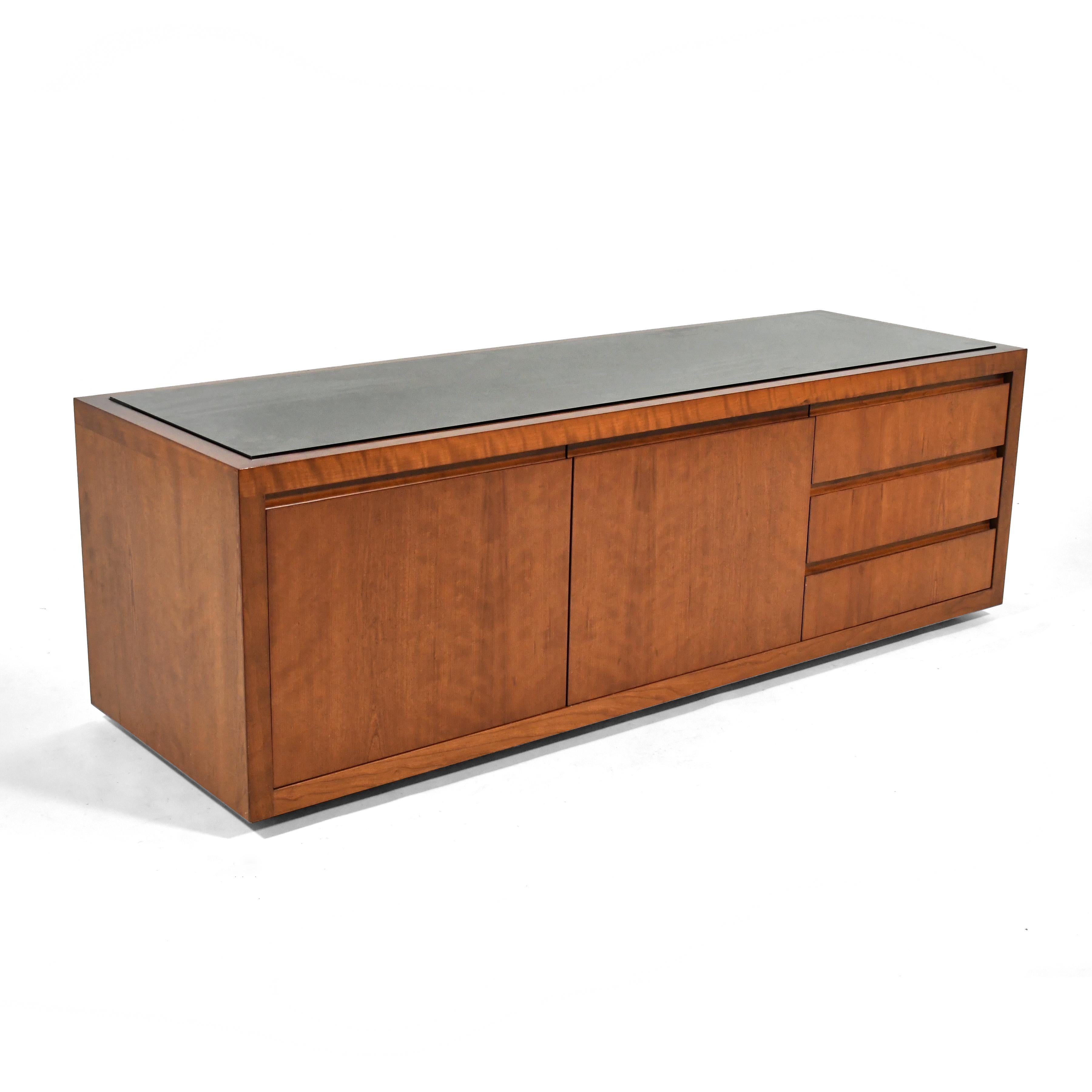 This handsome low cabinet by Conde House has three drawers, two doors that conceal a compartment with an adjustable shelf, and an inset top of smoked glass. It is perfect for use behind a sofa, along a wall with a large window, or as a media