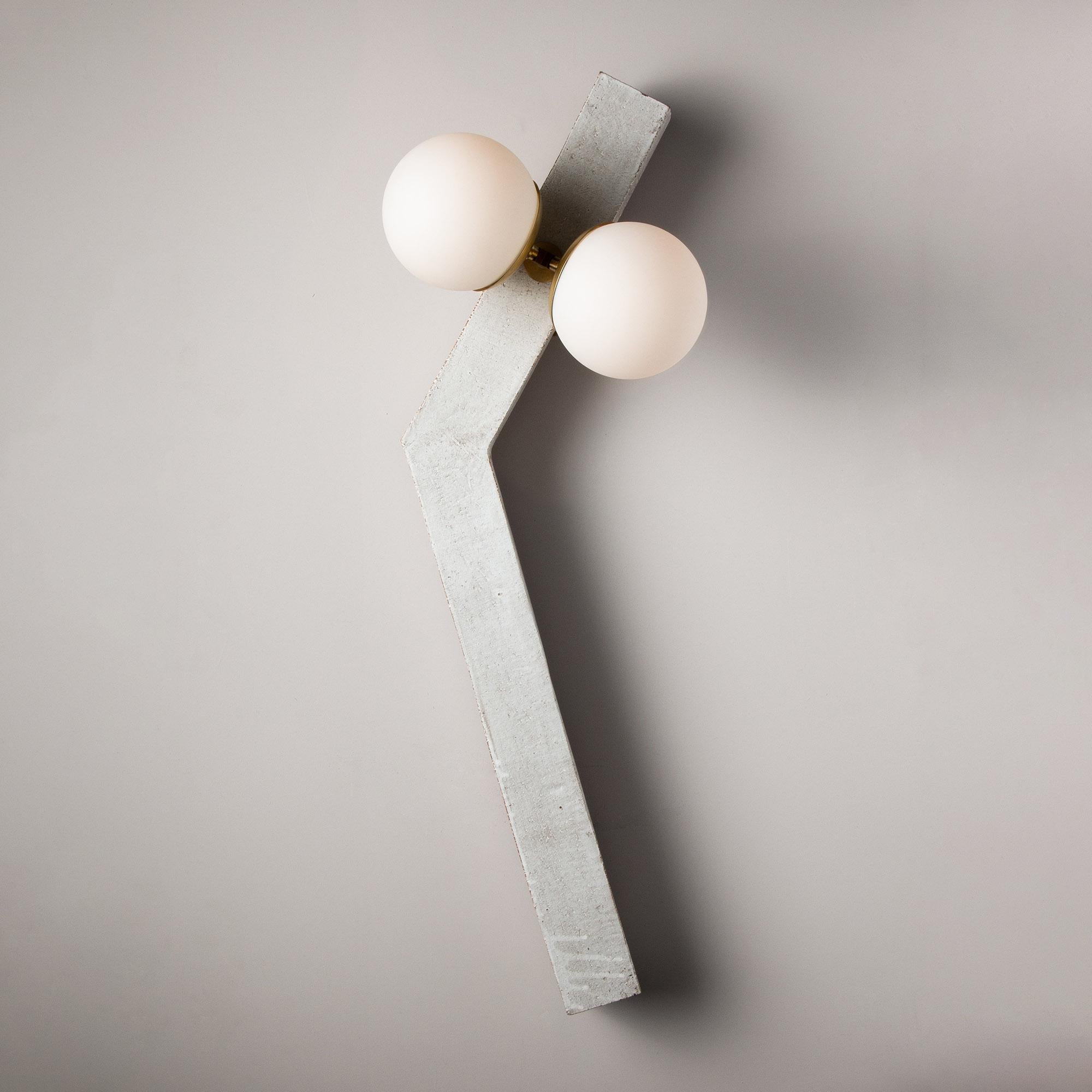 Inspired by midcentury Brutalist architecture and building materials, this playful handmade sconce balances a strong substantial ceramic base with delicate brass hardware and matte white glass. The angled ceramic center column is handcrafted from a