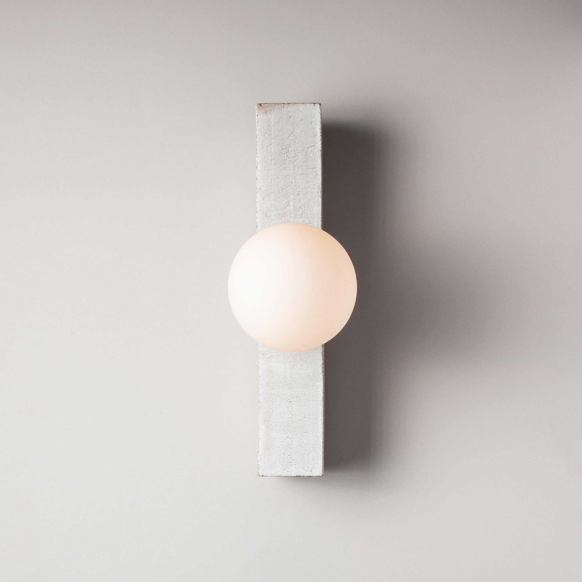 Inspired by midcentury Brutalist architecture and building materials, this minimal handmade sconce balances a strong substantial ceramic base with delicate brass hardware and matte white glass. The substantial ceramic center column is handcrafted