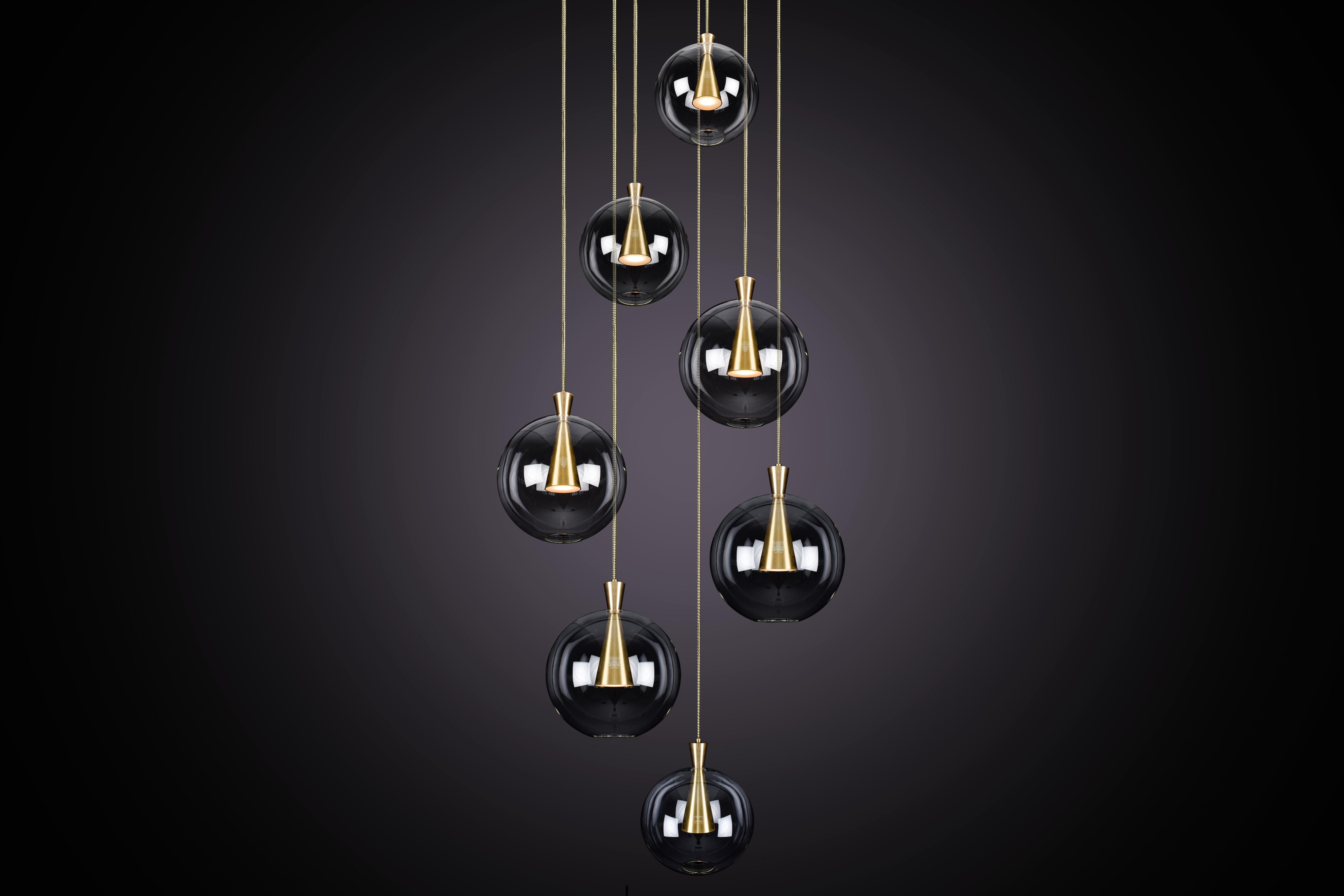 Cone está diseñado para mostrar la belleza y la elegancia atemporal de la simetría geométrica. Cada cono está mecanizado a partir de un bloque macizo de latón, con una pantalla de cristal soplado a mano delicadamente suspendida del vértice de los