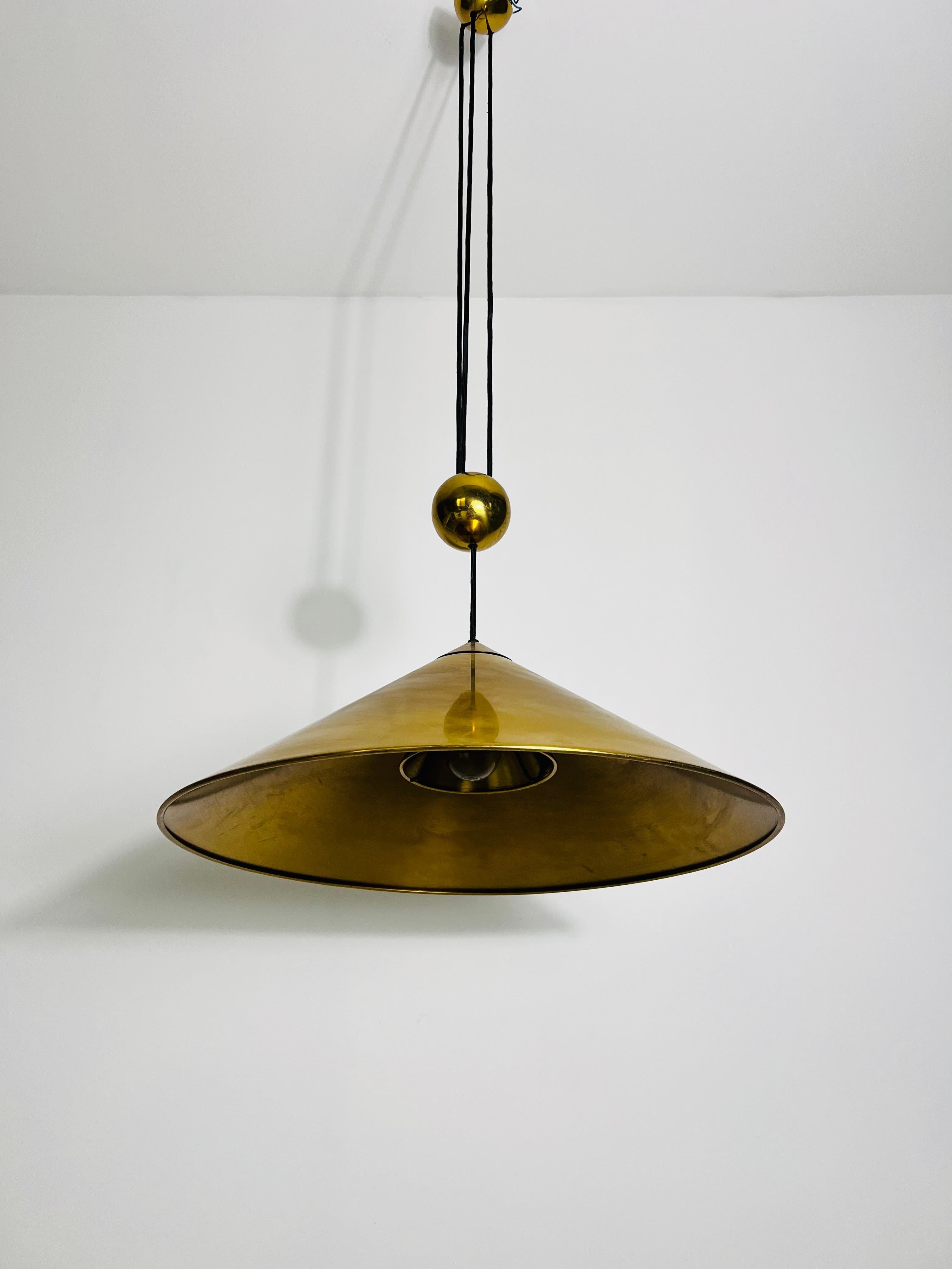 Disegnata da Florian Schulz e realizzata in Germania negli anni '70, questa lampada a sospensione da banco affascina per il suo design elegante e funzionale. La lampada presenta un raro paralume a forma di cono, un design insolito per Schulz, che