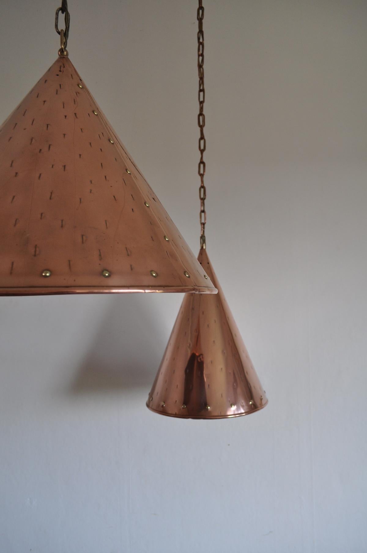 A set of 2 handcrafted Danish cone shaped copper pendent lamps with beautiful brass details. Made in Denmark in the 1970s.

Signs of wear consistent with age and use.

Measures: Height 38,5 cm, diameter 29 cm.
Height 35 cm, diameter 41,5