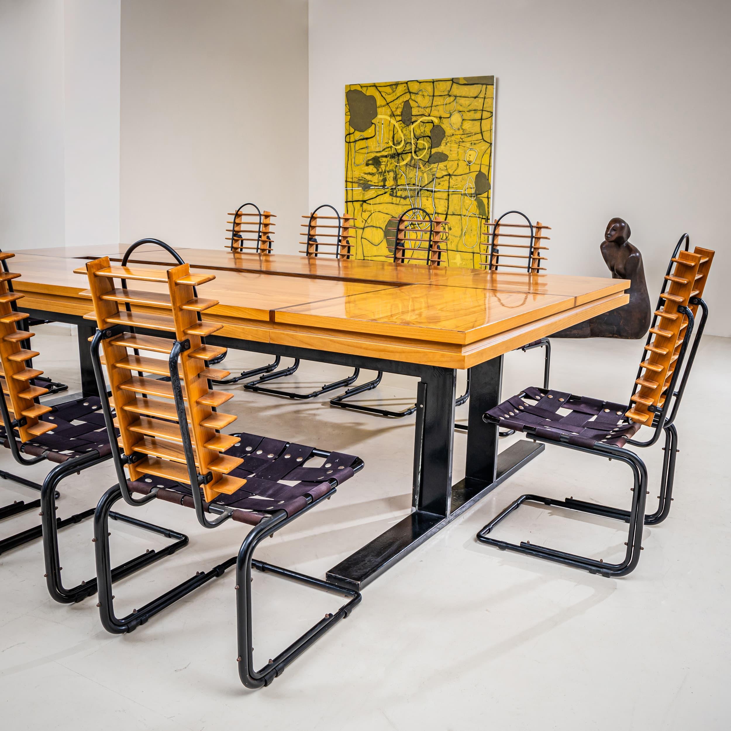 Large, architecturally composed conference table accompanied by ten sculptural chairs made of beechwood with black metal frames. The chairs feature horizontal slat backs and a minimalist, geometric design. The table stands on black metal legs and is
