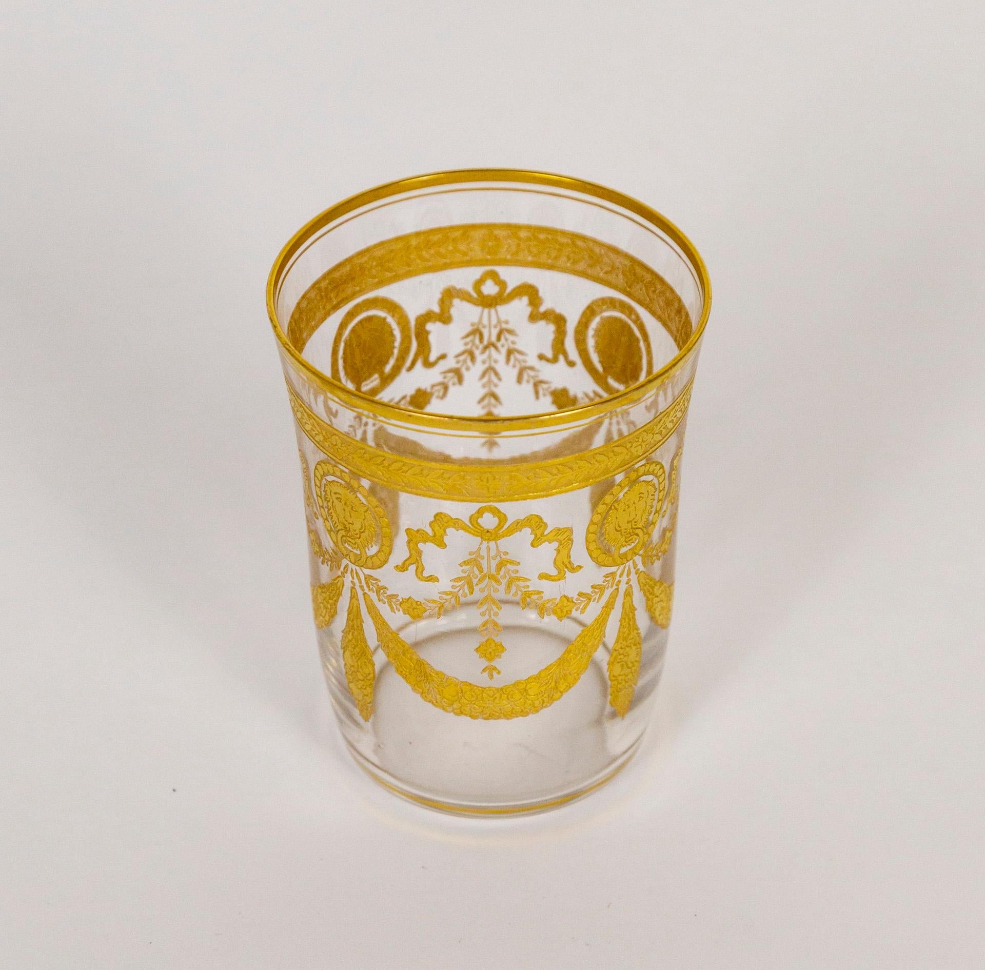 A set of 11, antique, mouth-blown, tumblers; etched, with an intricate gold motif of ribbon, floral garlands, and lion faces- the 