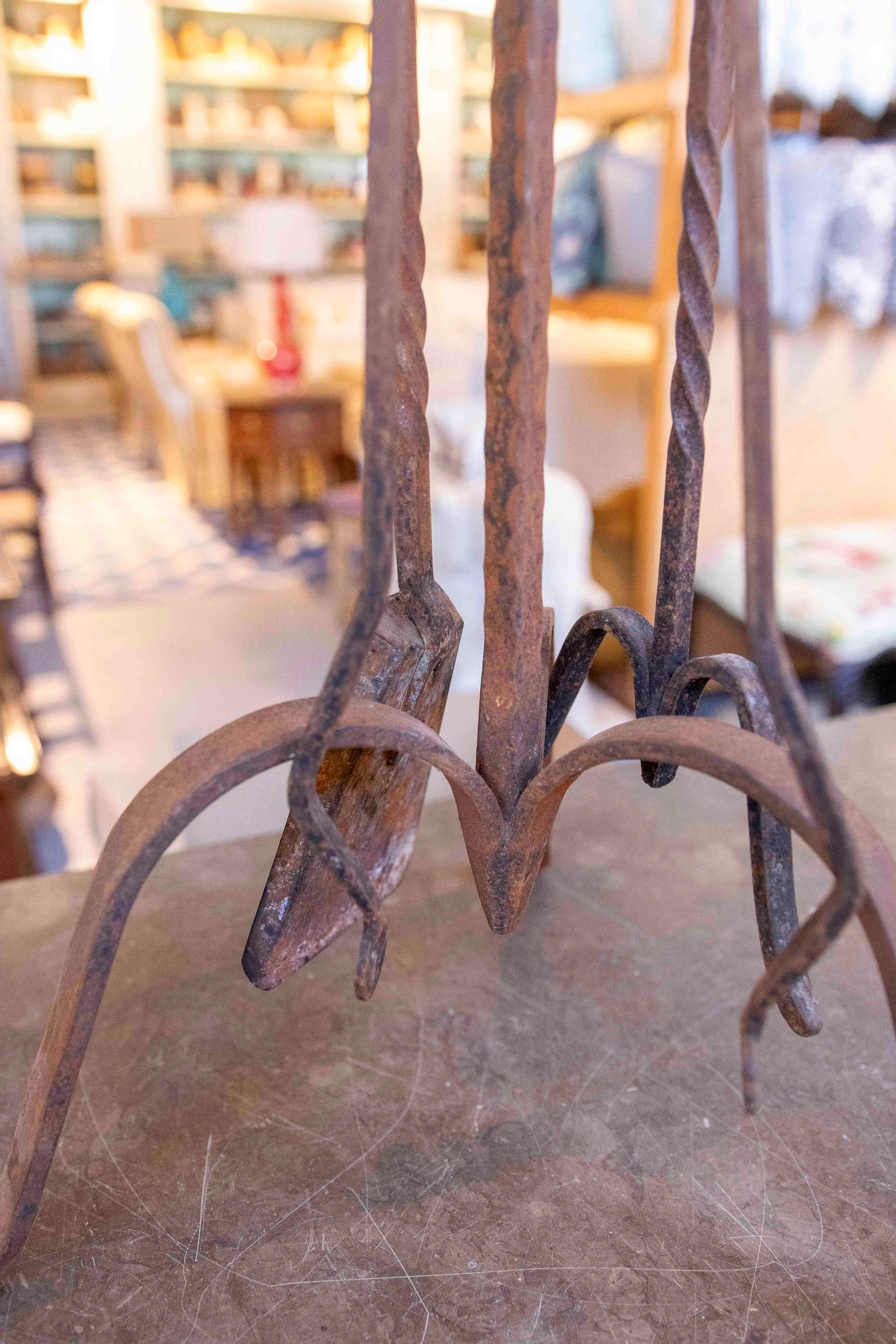 Conjunto de herramientas de chimenea en hierro forjado, realizado a mano a finales del siglo XIX. Incluye soporte y tres utensilios con mangos trenzados de diseño ornamental, que reflejan la maestría artesanal del forjado tradicional. Su pátina