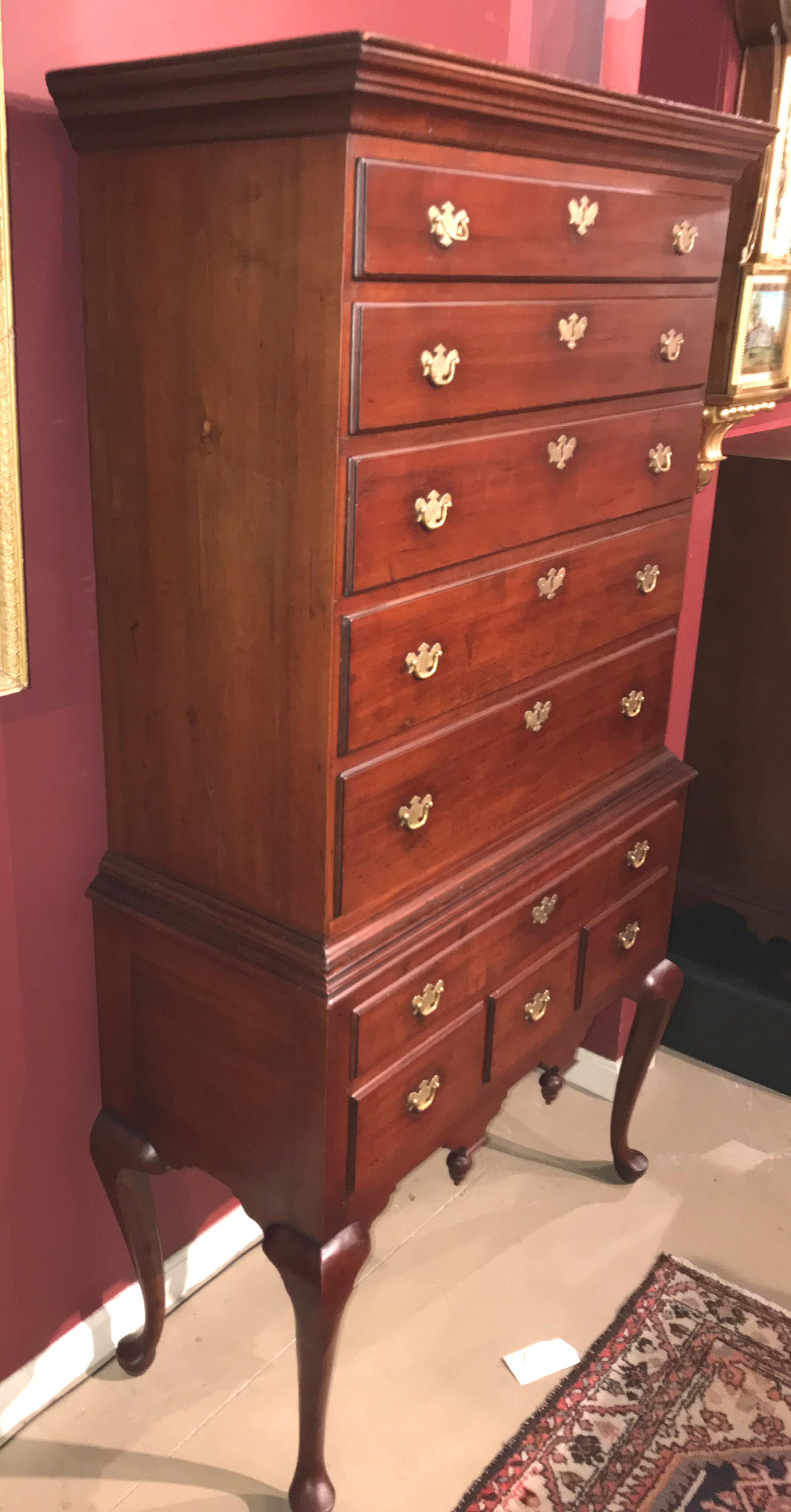 A fine two-part maple flat top highboy, its upper case with a molded cornice surmounting five graduated long drawers, over a lower case with a single long drawer over three fitted drawers, with a nicely carved skirt featuring two acorn drops, all