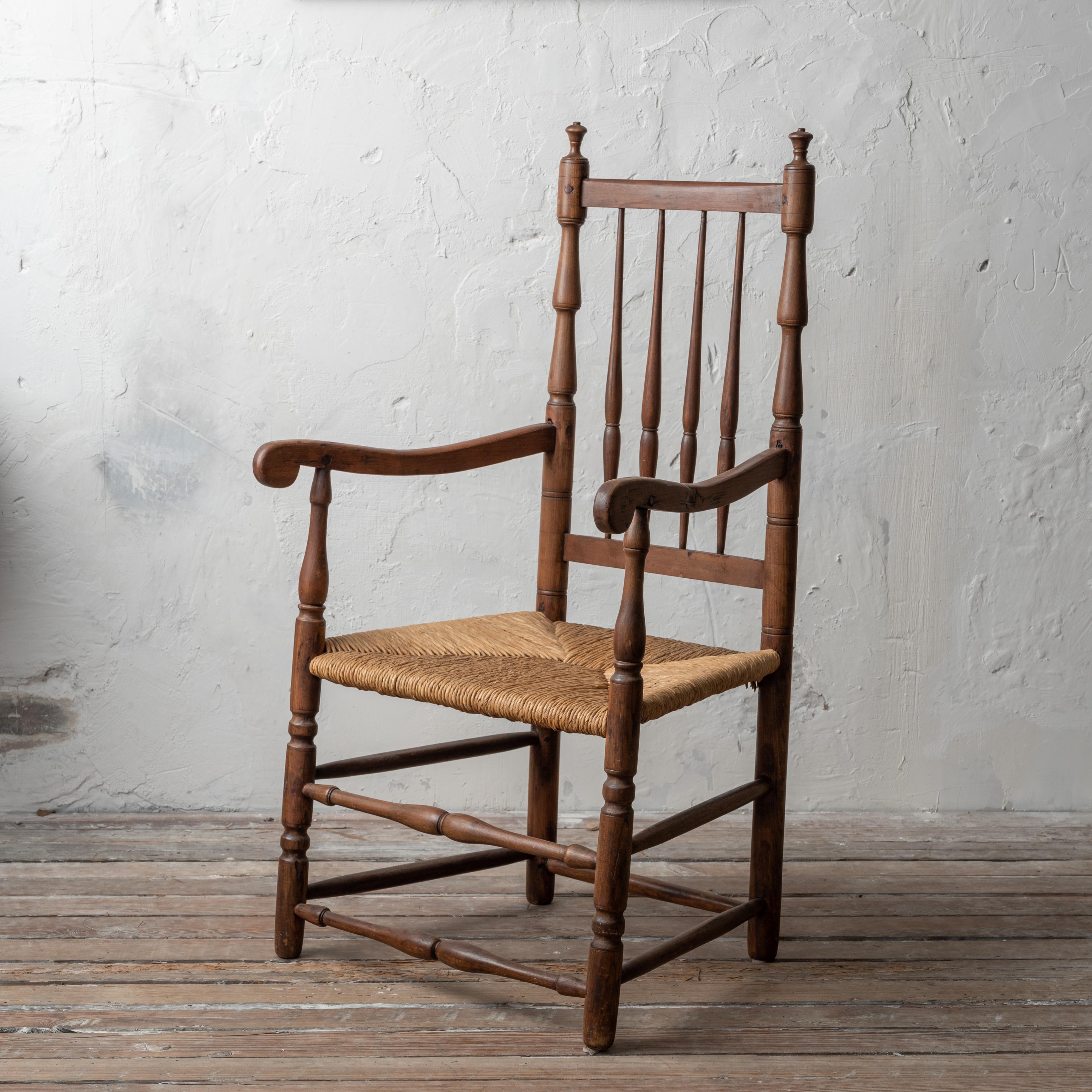 A Connecticut William & Mary bannister-back rush bottom armchair with straight rails and spindle back in maple, circa mid-18th century.  

23 ½ inches wide by 20 ½ inches deep 42 ¼ inches tall; seat height 16 inches



