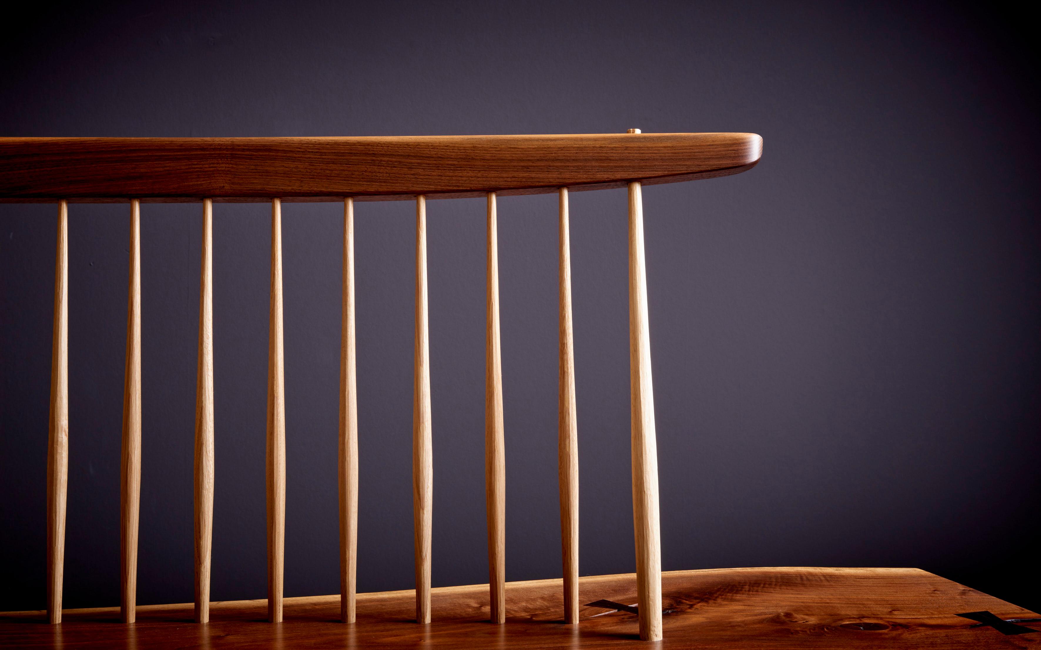 Conoid bench in walnut, US 2021, by Mira Nakashima based on a George Nakashima design. The Bench is made in black walnut with hickory spindles. 
 