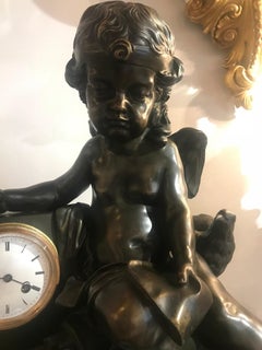 Une magnifique horloge en bronze représentant Cupidon en train de reposer