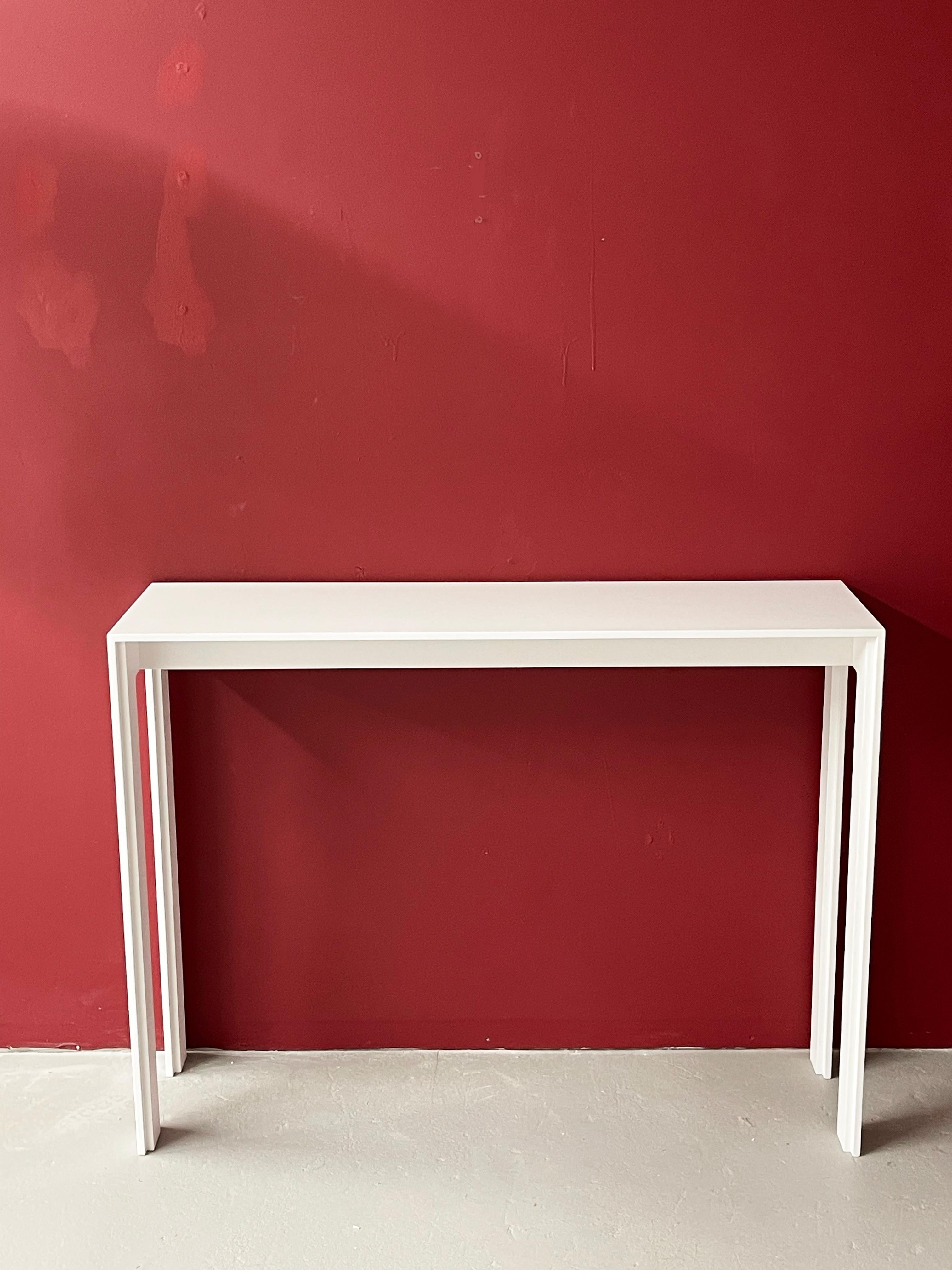 This elegant console combines subtle while elaborate design in a durable modern material.
The top and legs are designed with recessed edges, like a picture frame to encompass the void. The subtle front from contrasts with the side views featuring