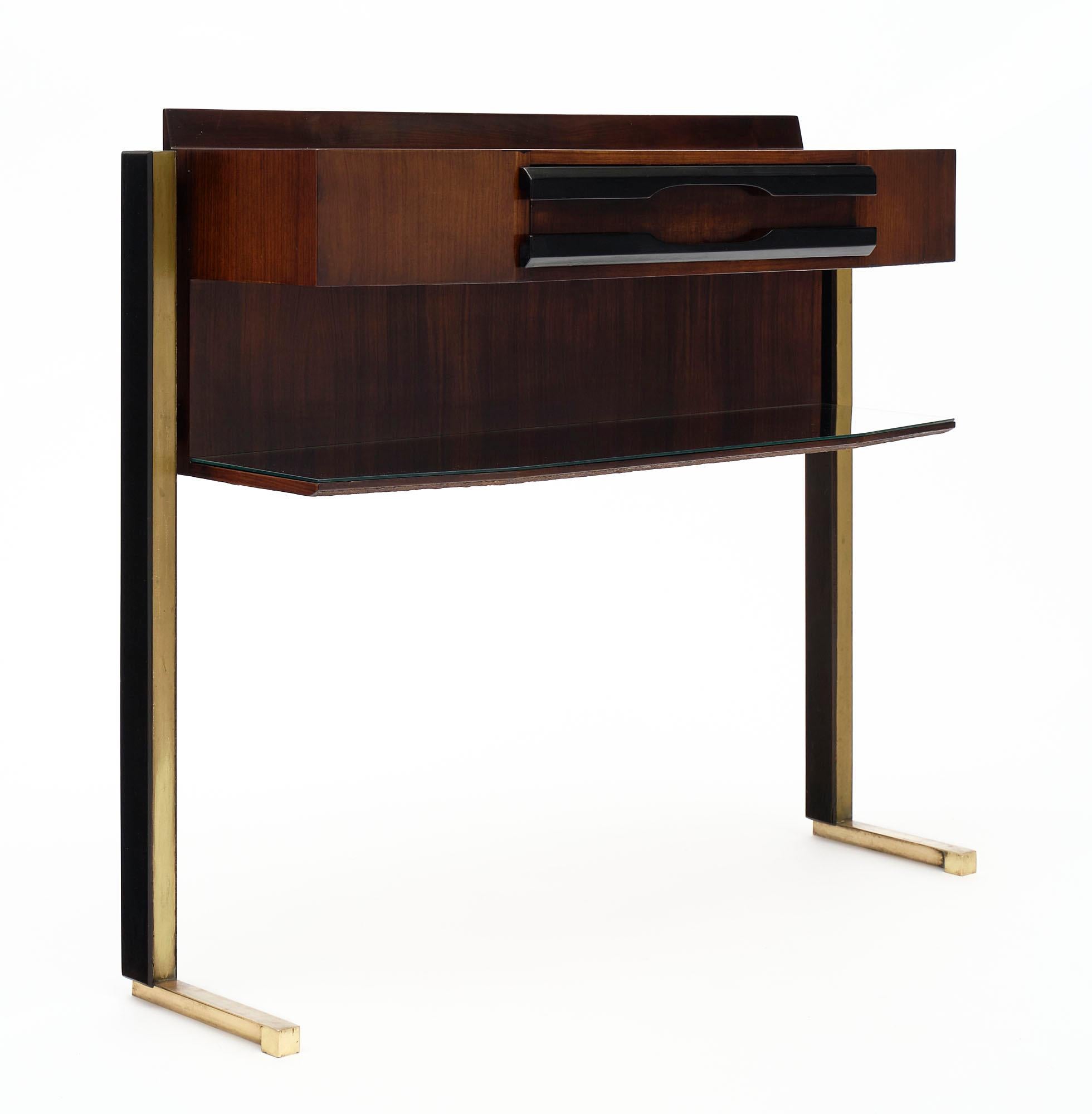 Console and mirror, Italian, made of Brazilian rosewood and ebonized rosewood. There is a mirror covered shelf and brass legs. This set is made by designer Carlo di Carli. A square frame holds a circular mirror above the console. We love this set.