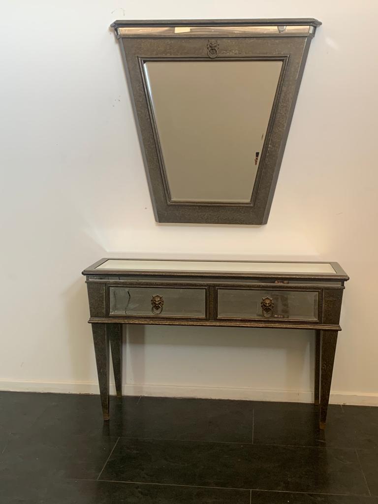 Console with mirror produced by Lam Lee Group of Dallas, the style refers to the French eclecticism of 1940. Both the console and the mirror are made of wood covered with patinated metal leaf, combined with bronze details.

Price for